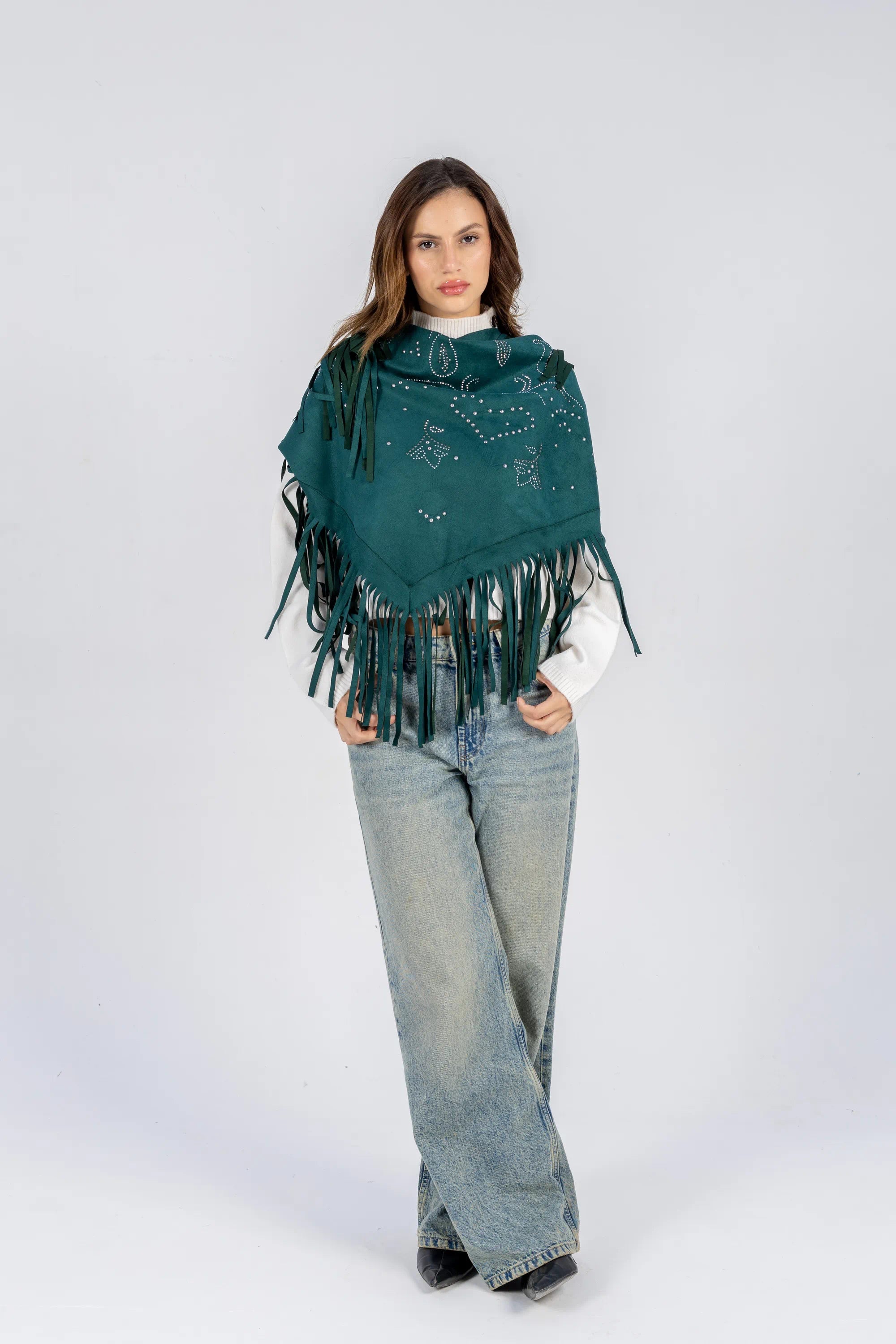 Woman wearing a teal poncho with fringe on a white background