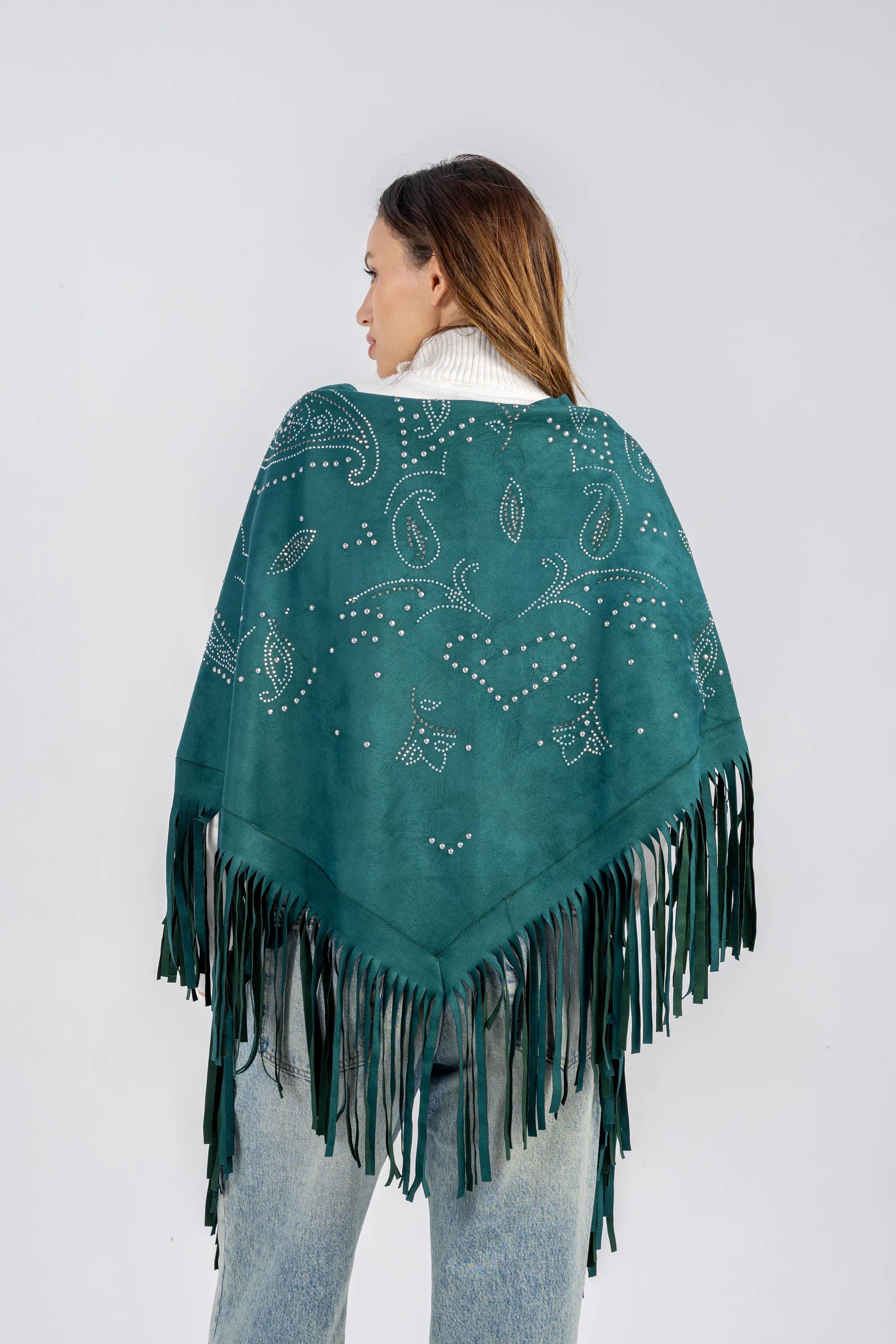 Woman wearing a teal poncho with fringe details on a white background
