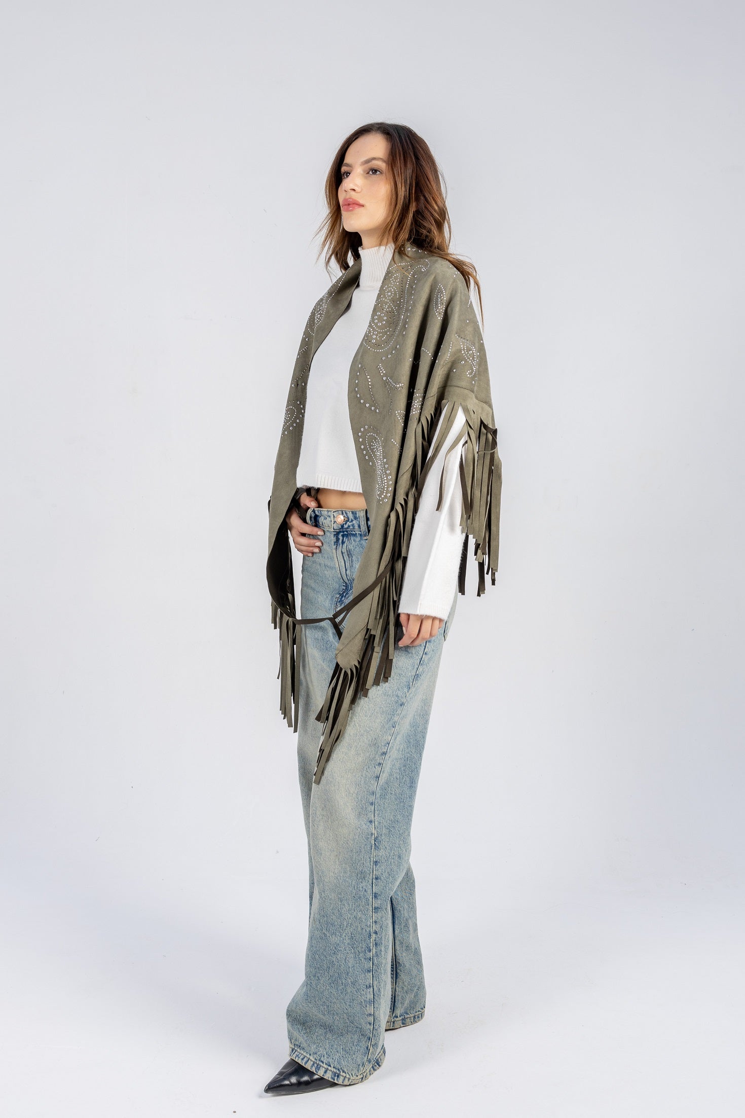 Woman wearing a green cardigan, white shirt, and blue jeans on a white background