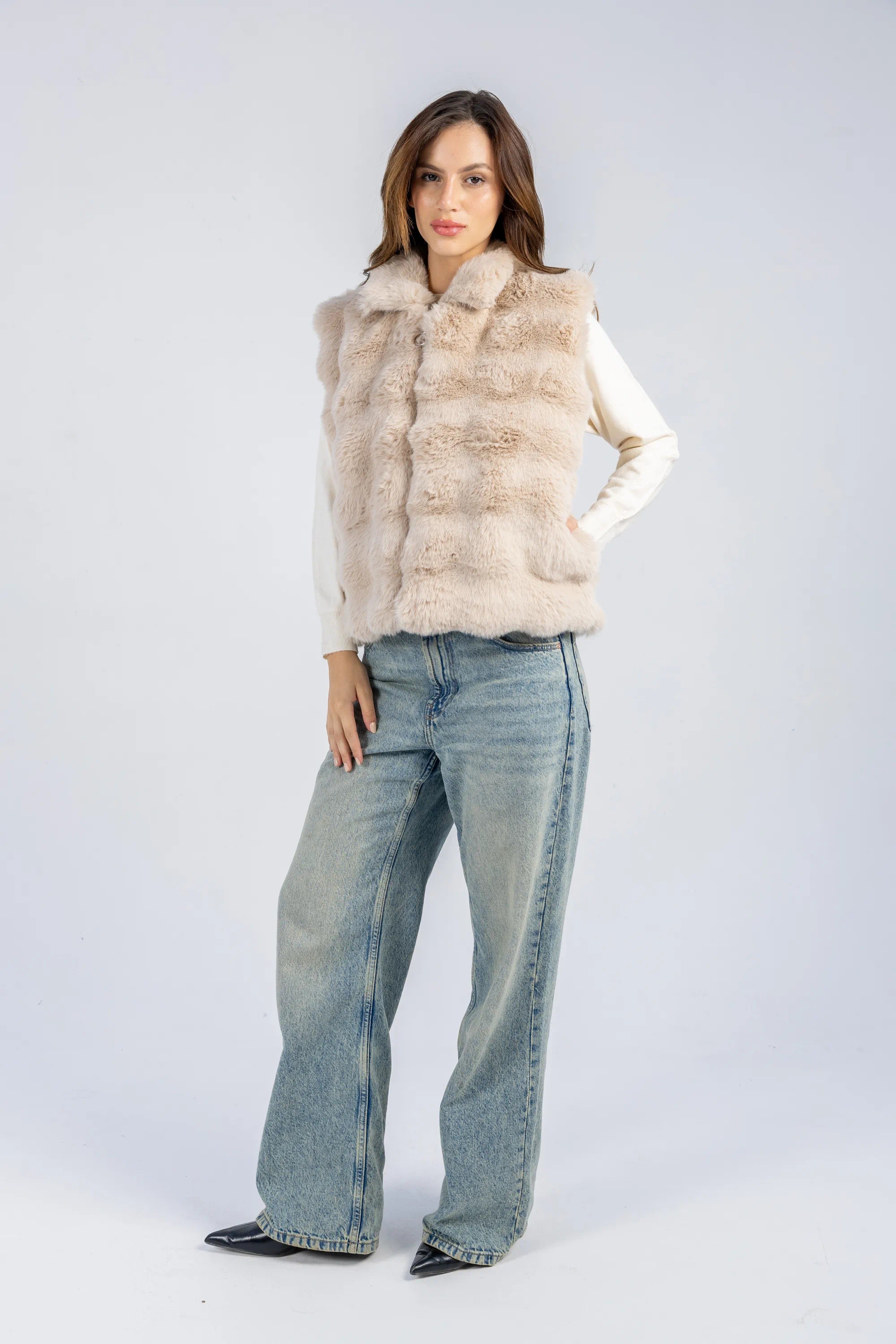Woman wearing a fur vest and jeans on a white background