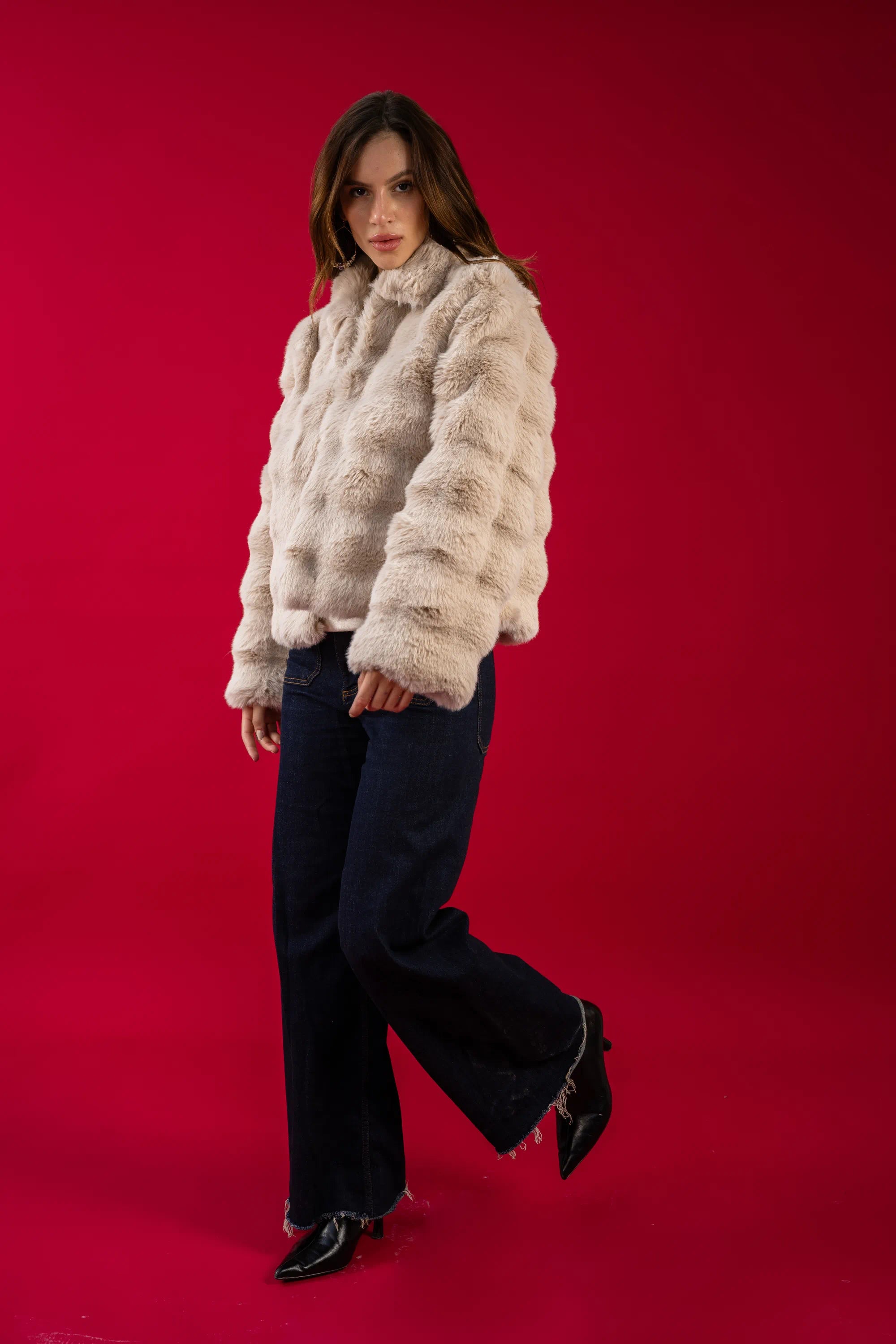 Woman wearing a fluffy white jacket against a red background