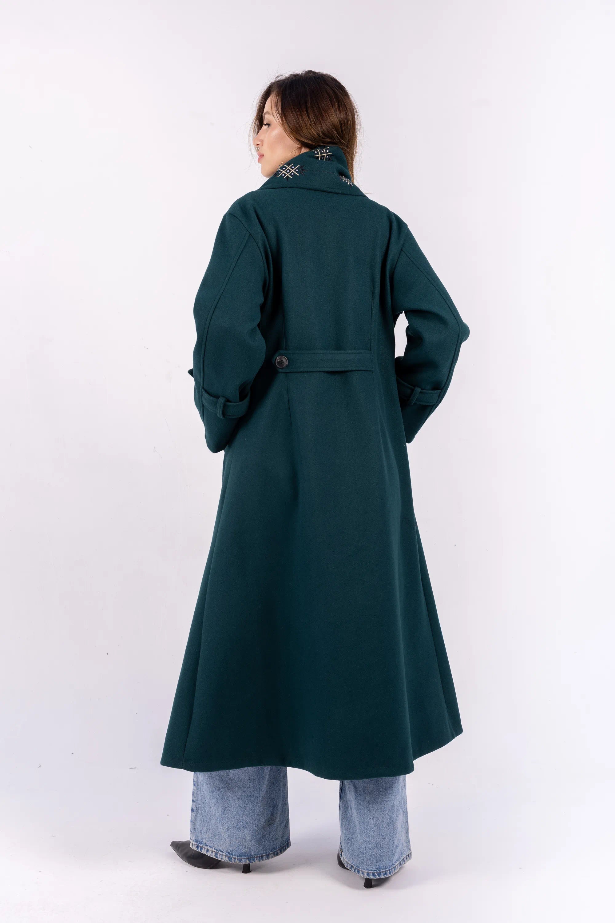 Person wearing a long dark green coat on a white background