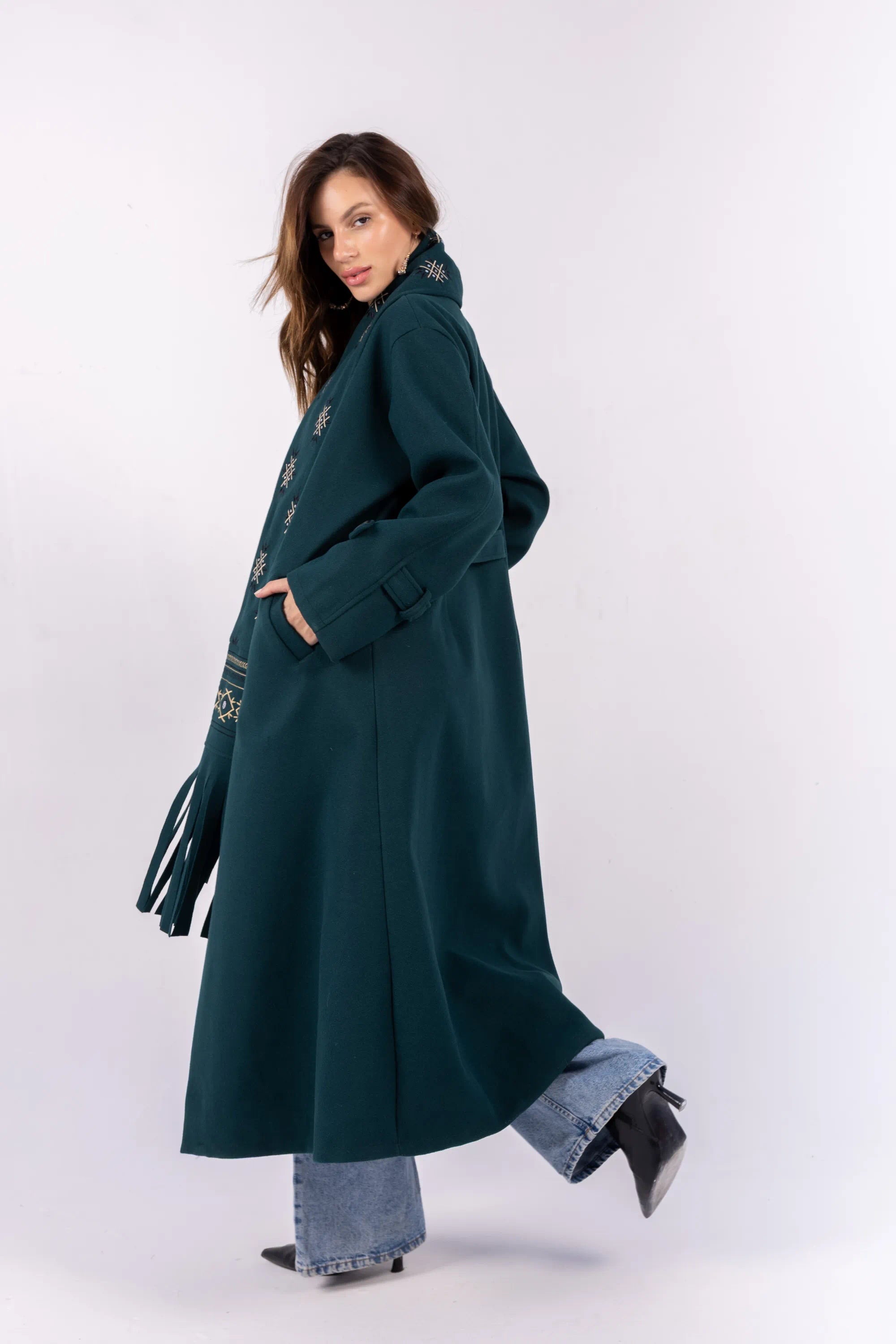 Woman wearing a long dark green coat on a white background