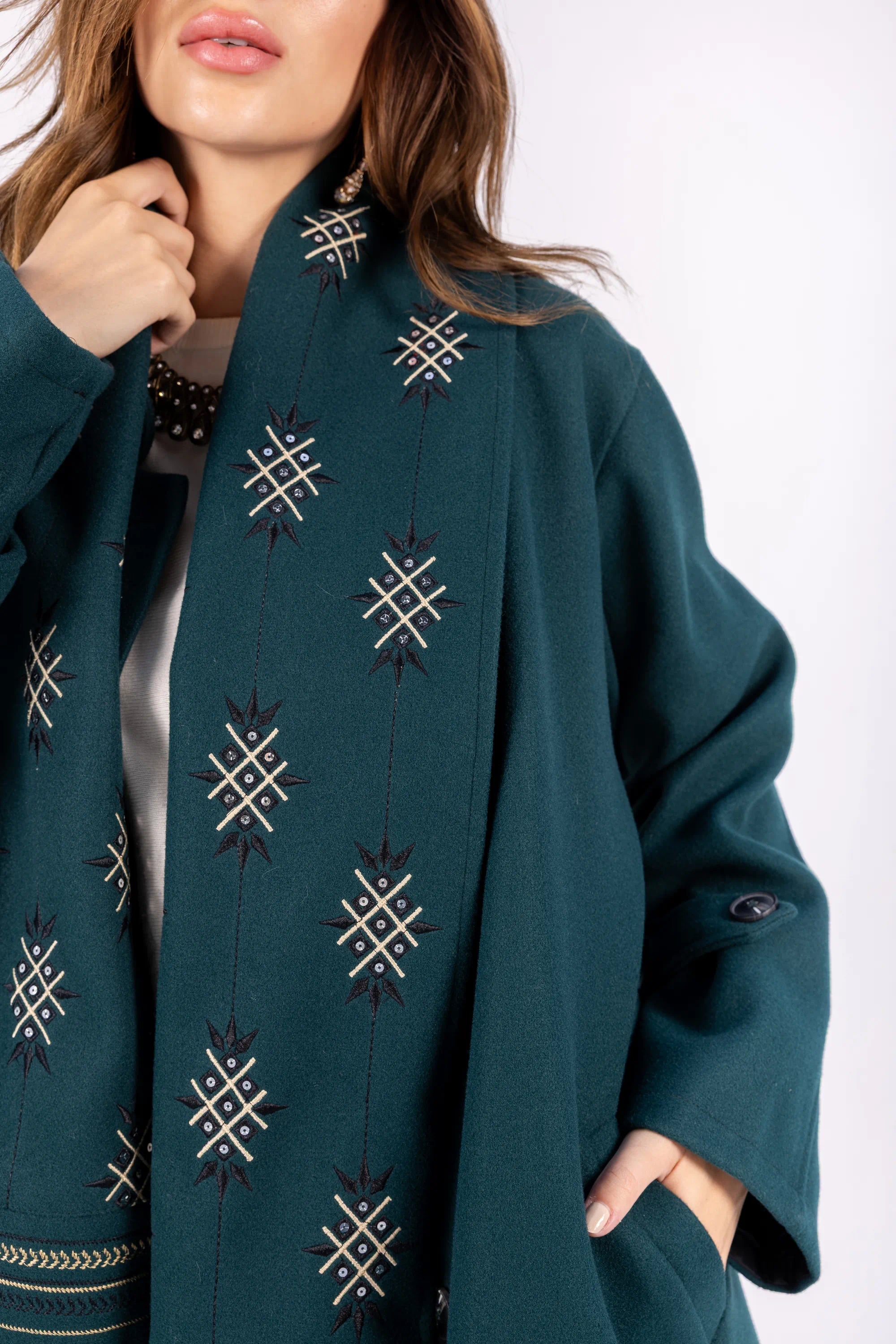 Teal coat with geometric patterns on a white background