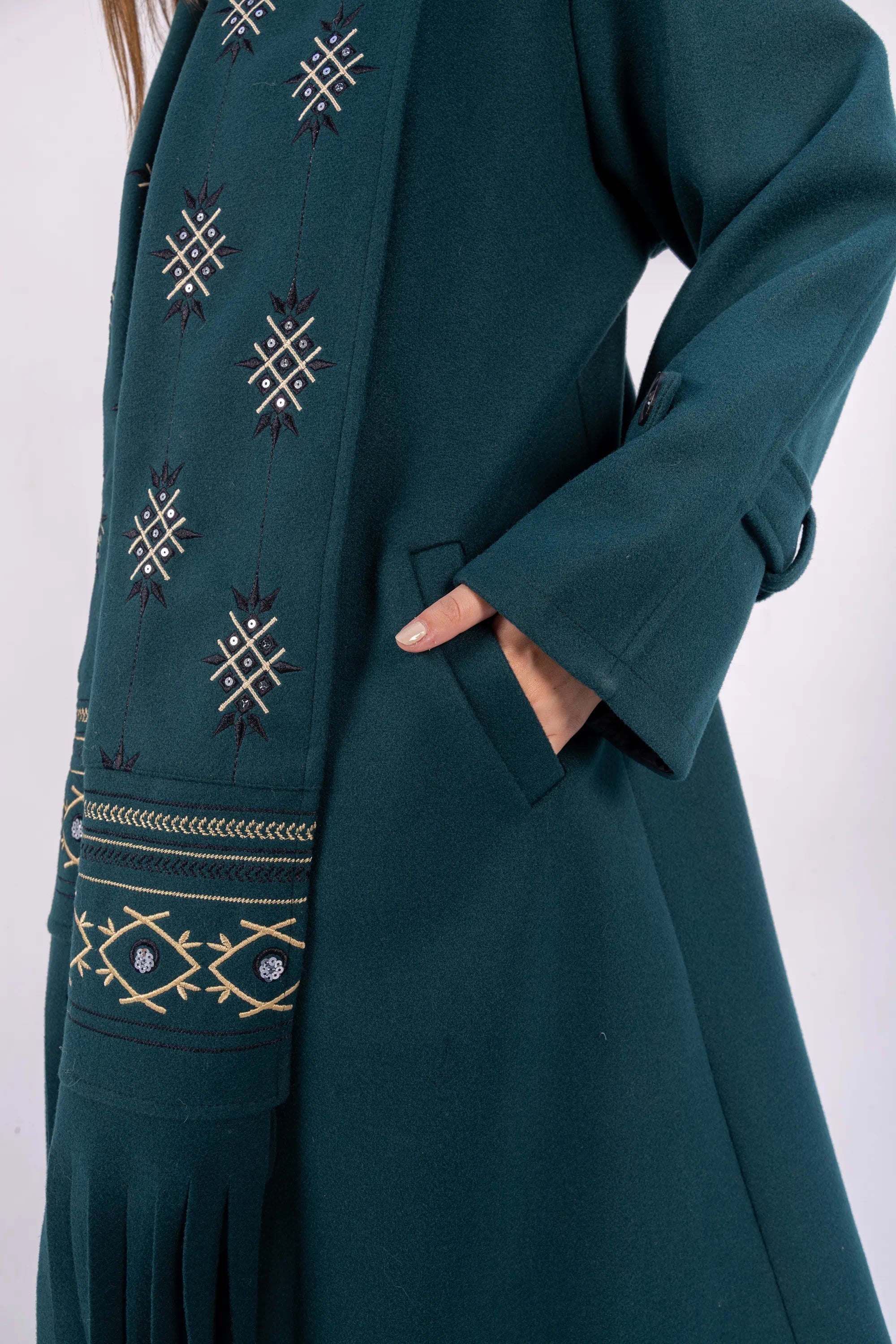 Green coat with intricate embroidery on a white background