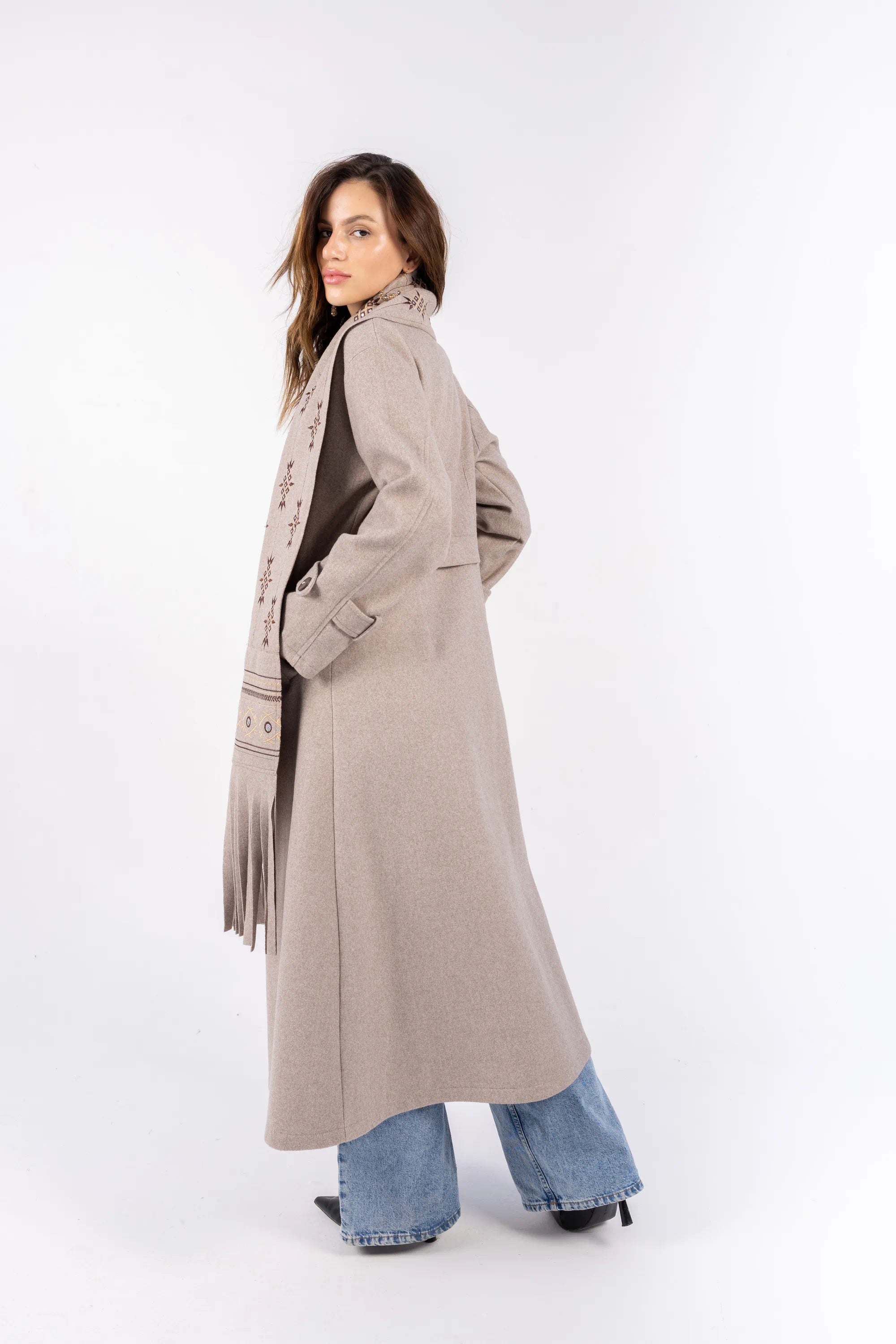 Woman wearing a long beige coat on a white background