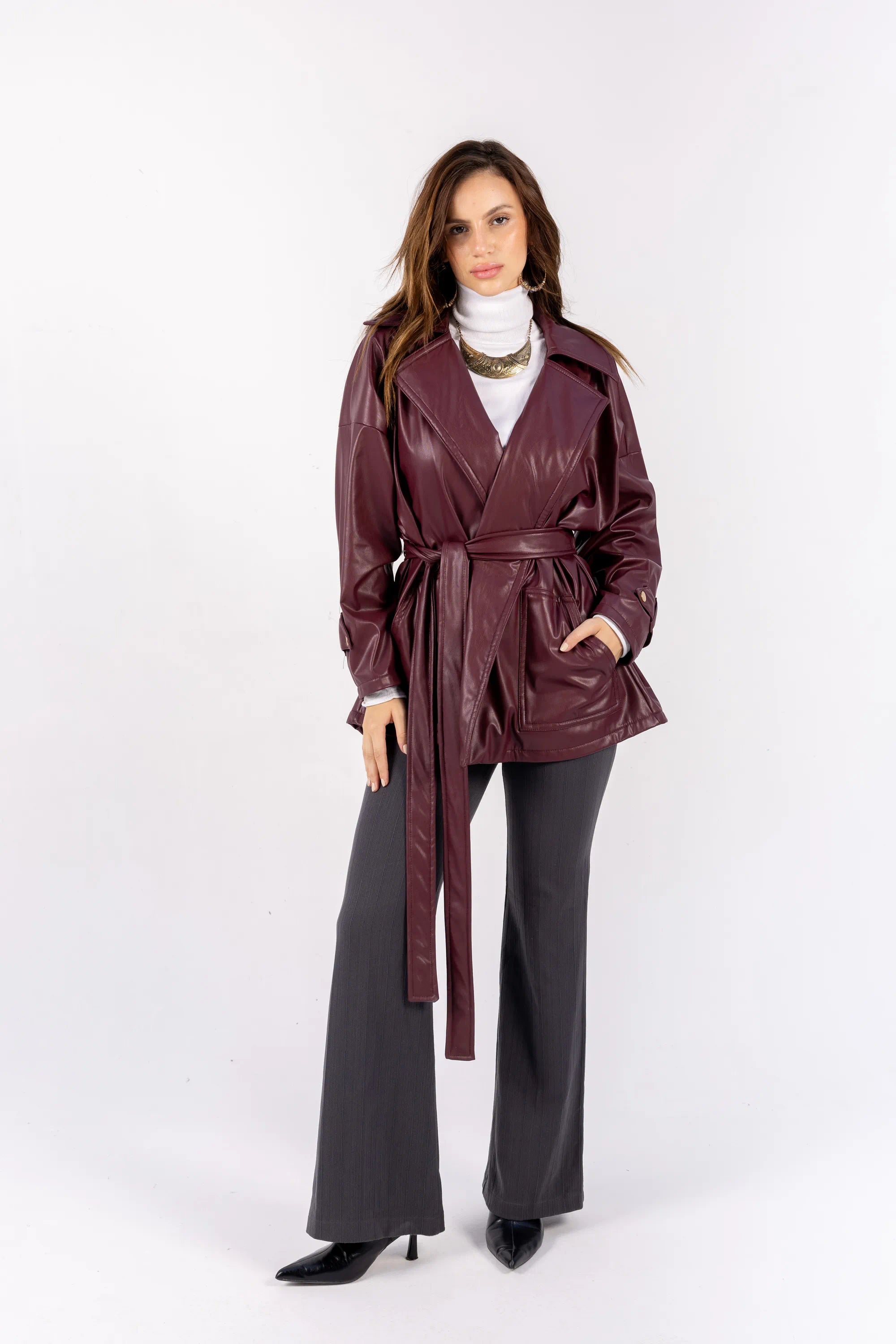 Woman wearing a burgundy leather trench coat on a white background
