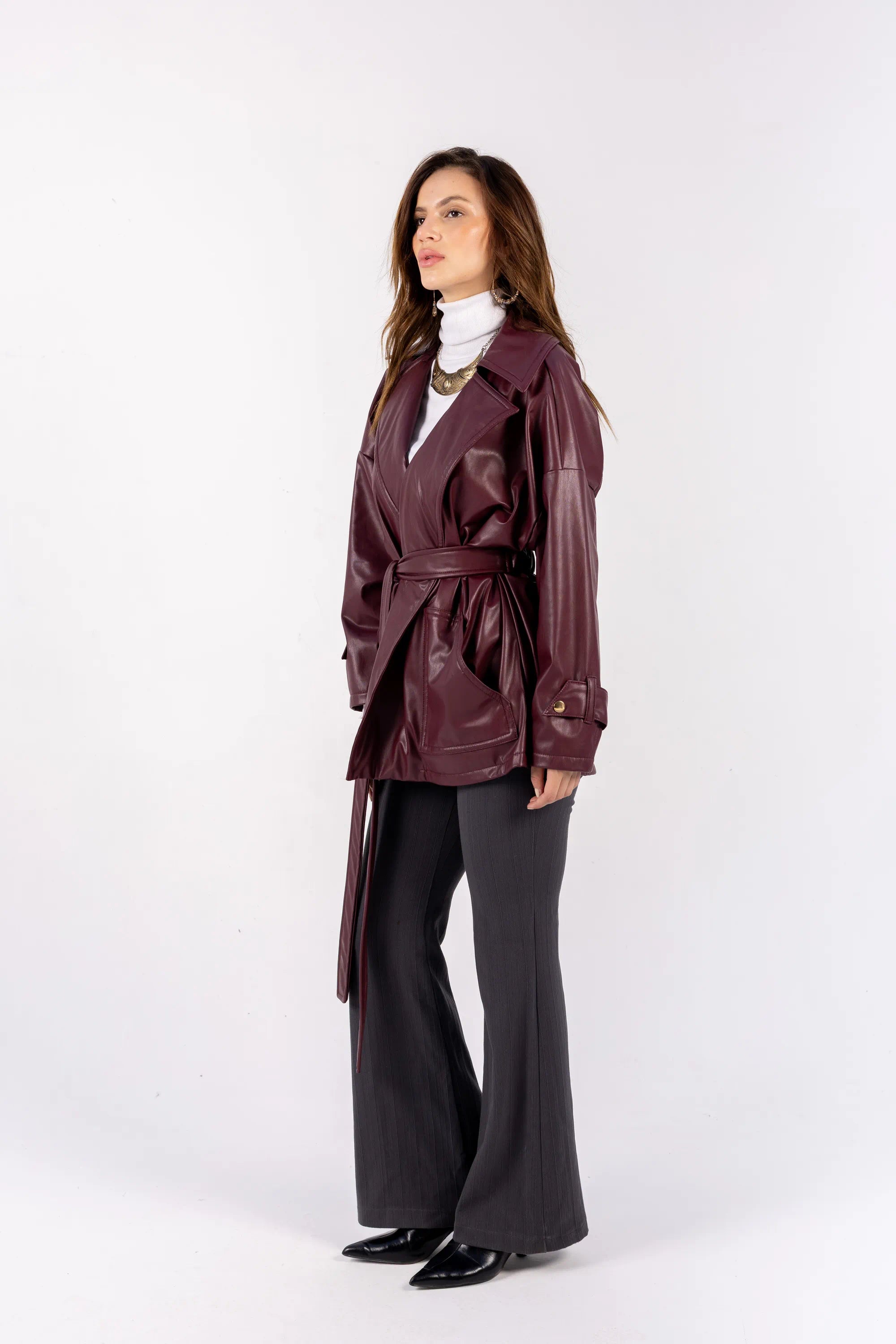 Woman wearing a purple trench coat and black pants on a white background