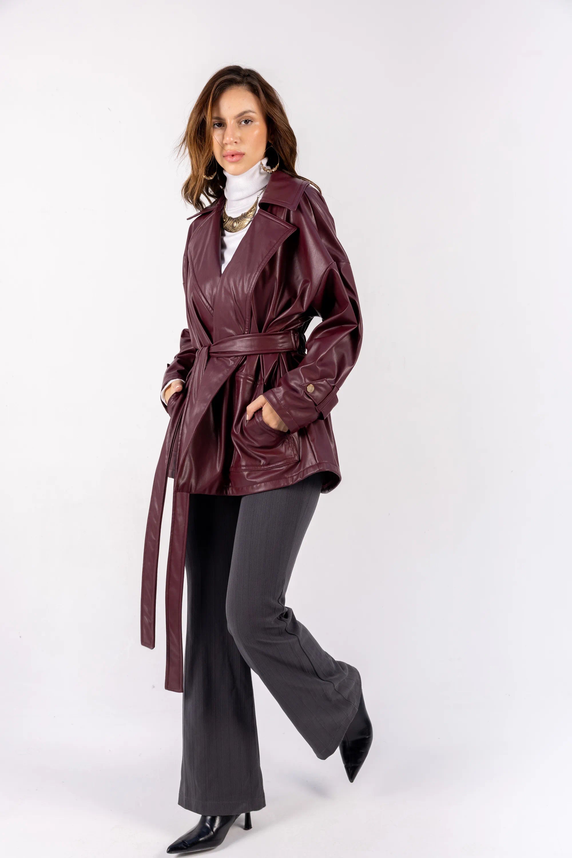 Woman wearing a burgundy trench coat on a white background