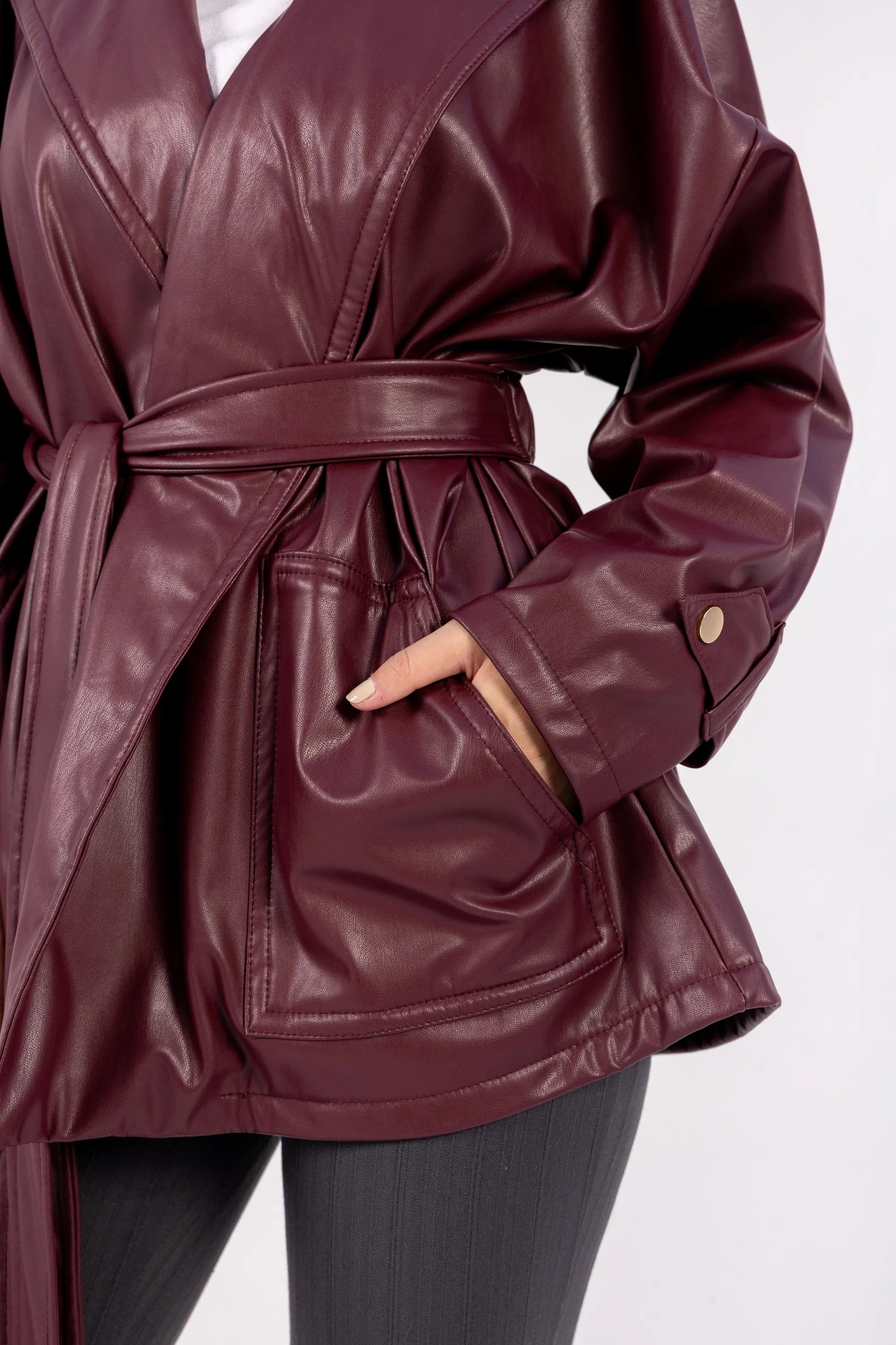 Maroon leather coat with a belt on a white background