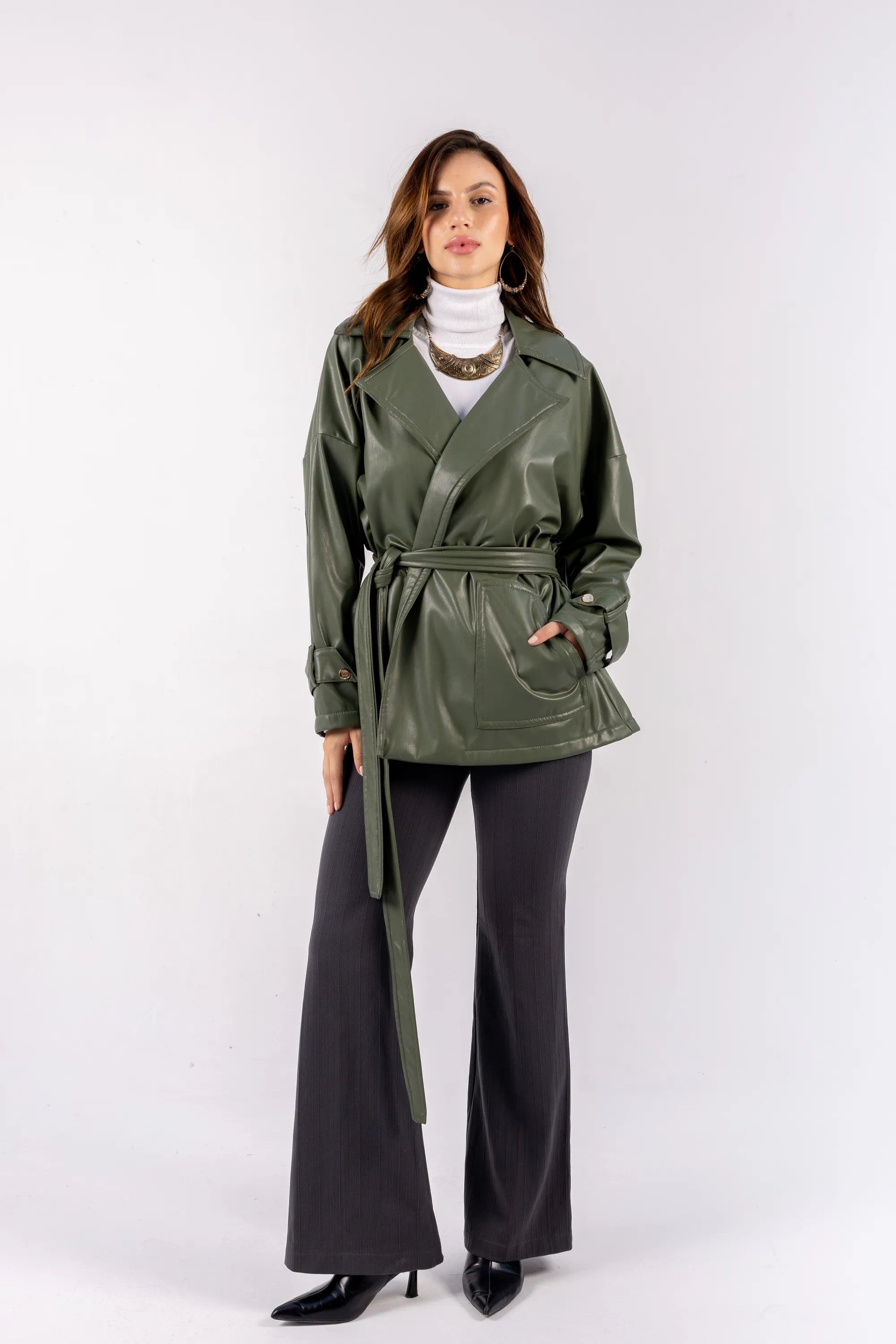 Woman wearing a green trench coat and black pants on a white background