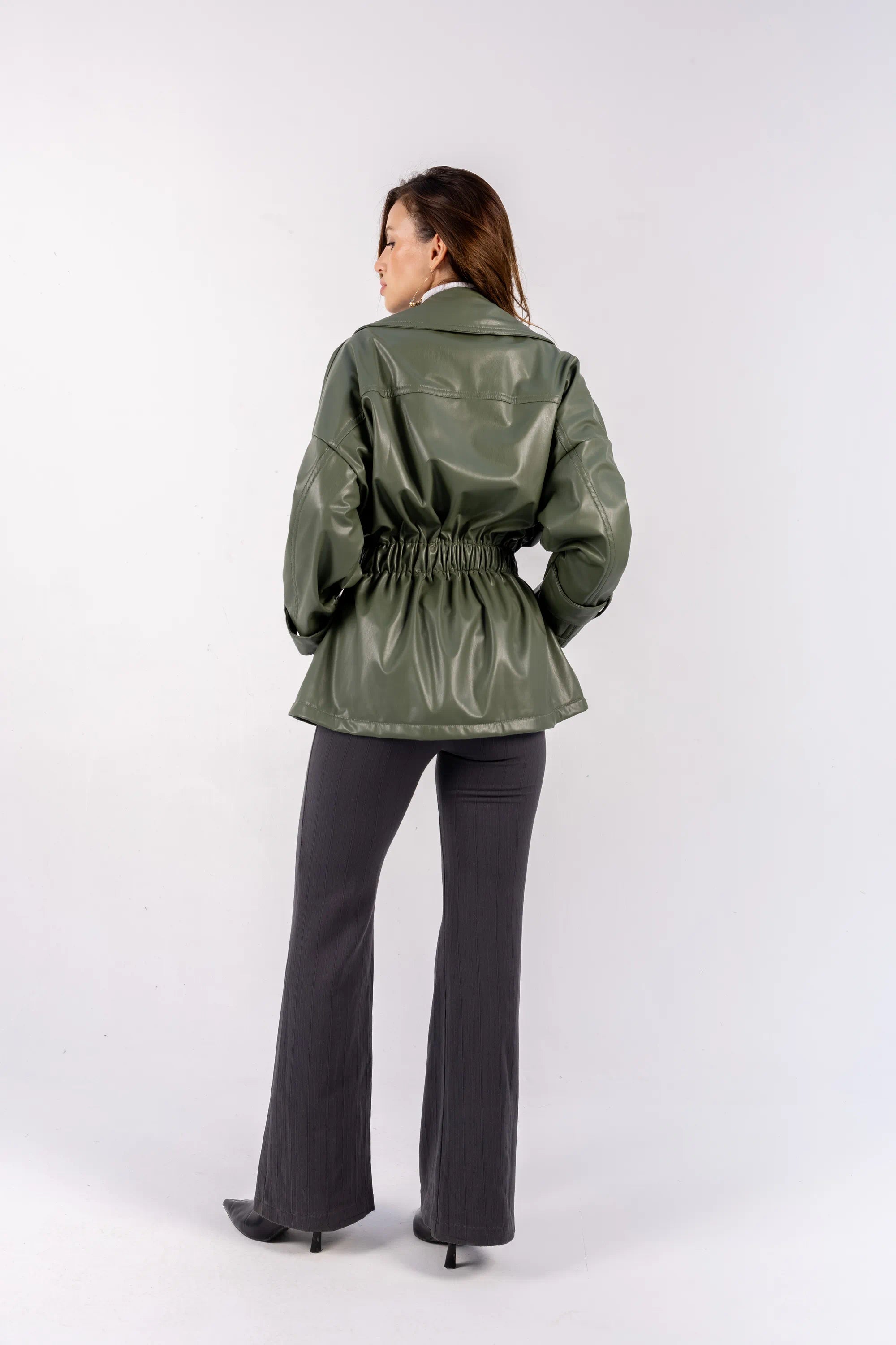 Person wearing a green raincoat and gray pants on a white background