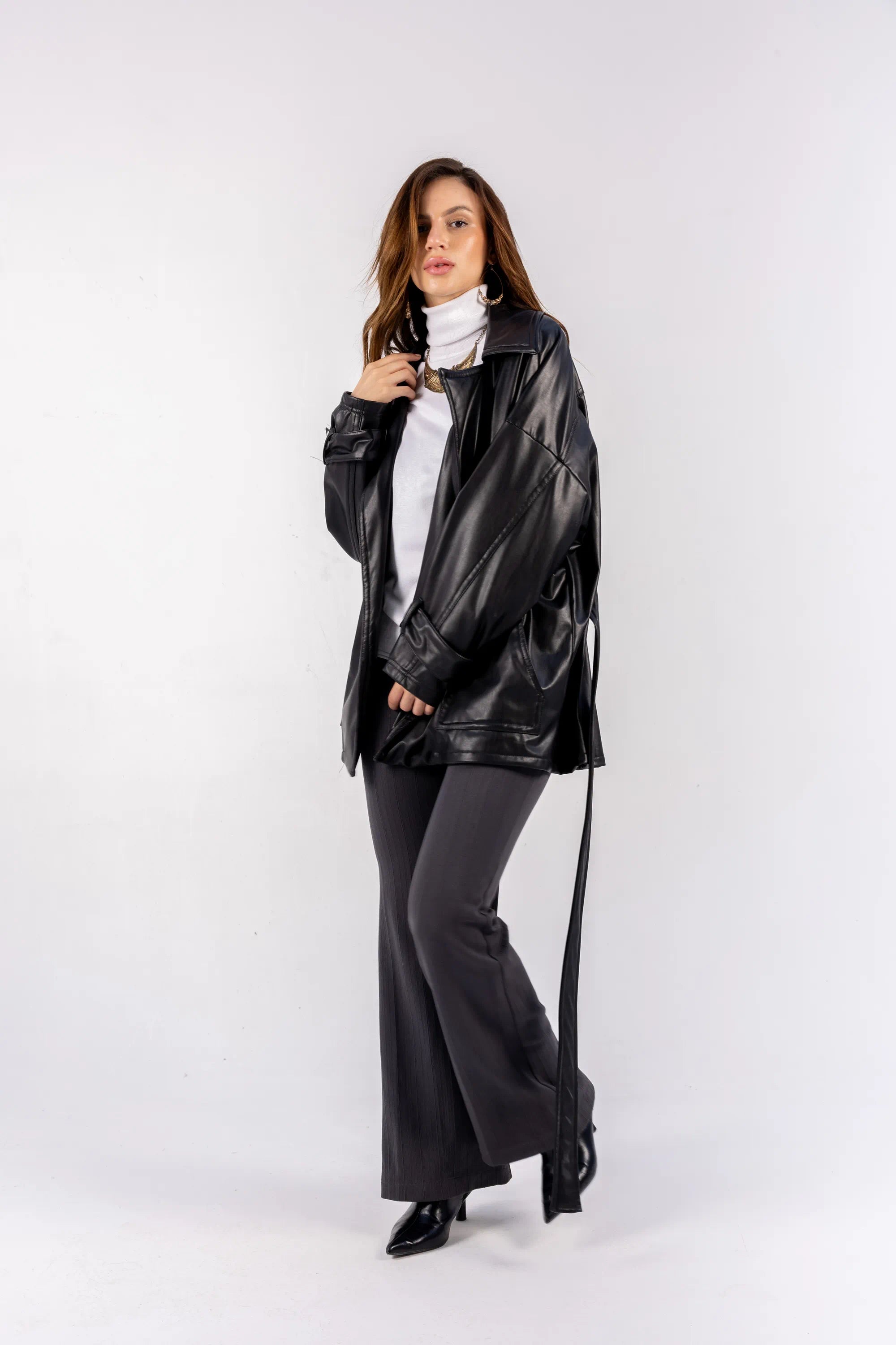 Woman wearing a black leather jacket and pants on a white background