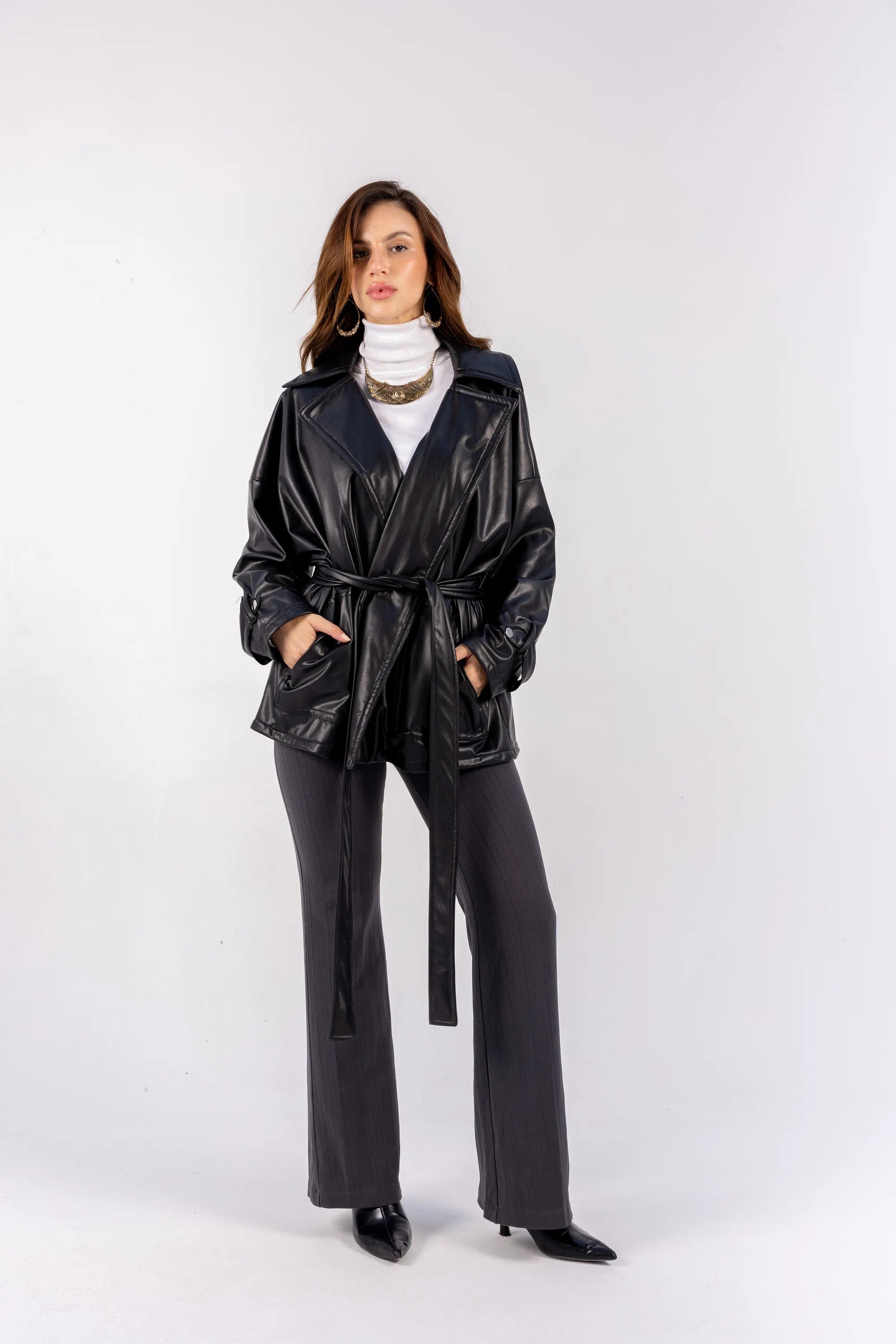 Woman wearing a black leather jacket and pants on a white background