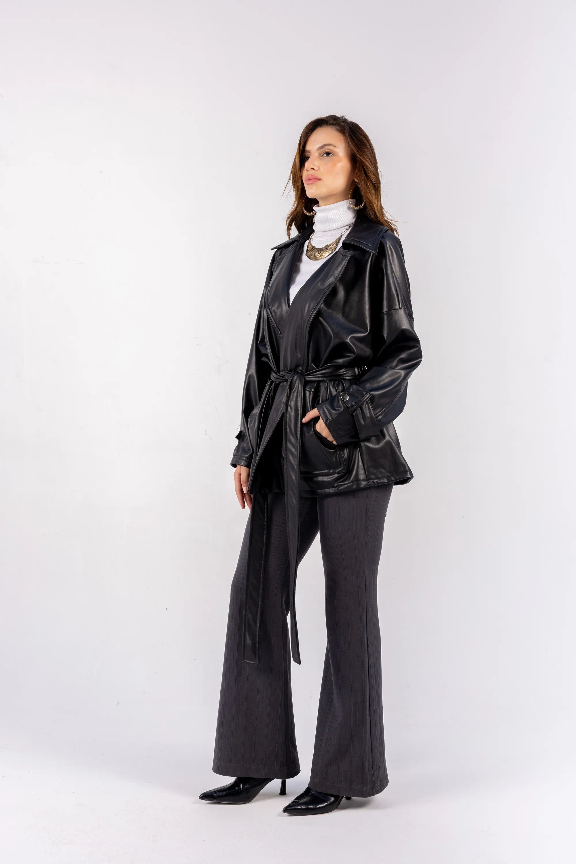 Woman wearing a black leather jacket and black pants on a white background