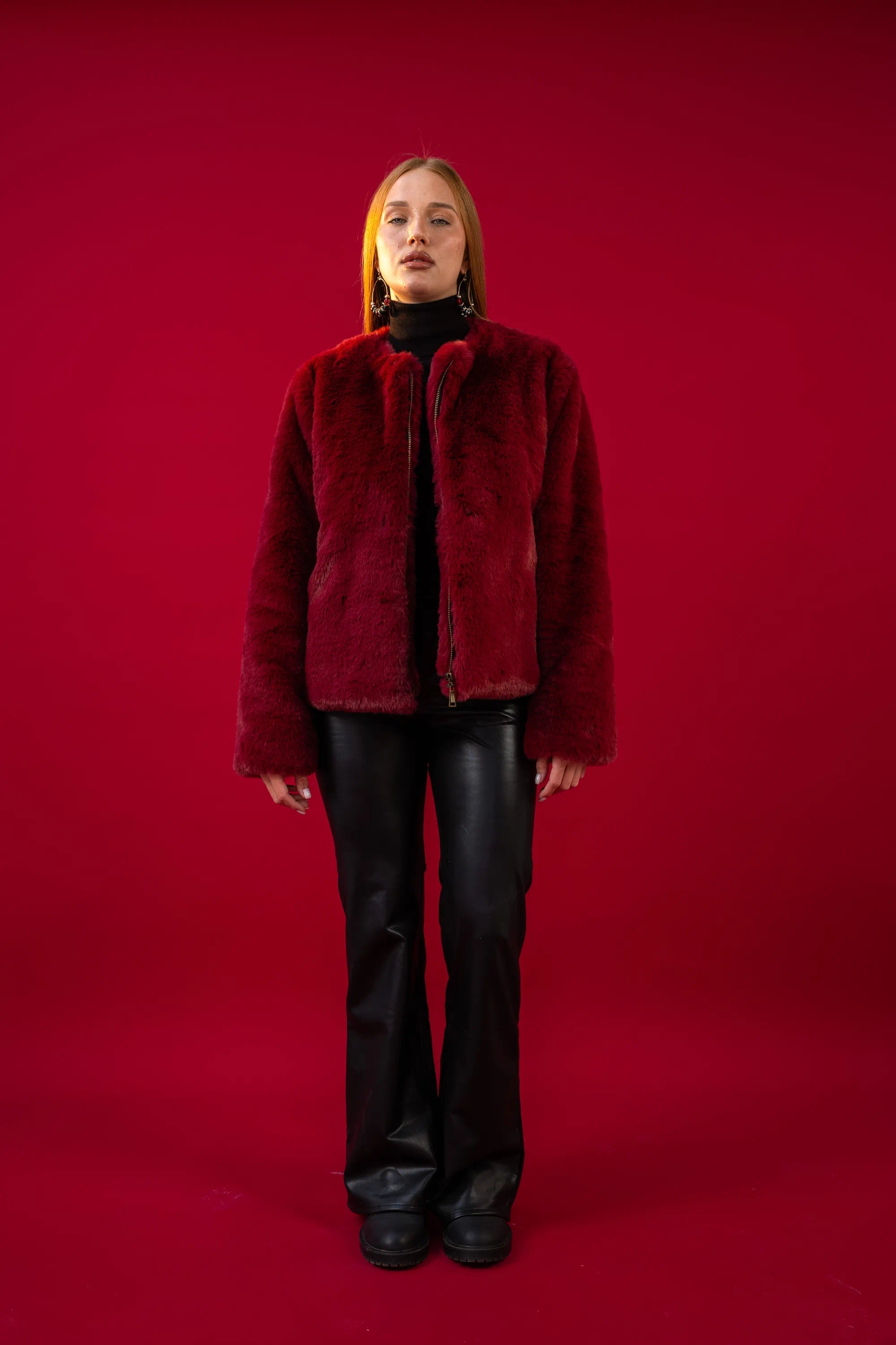 Person wearing a red fur coat against a red background