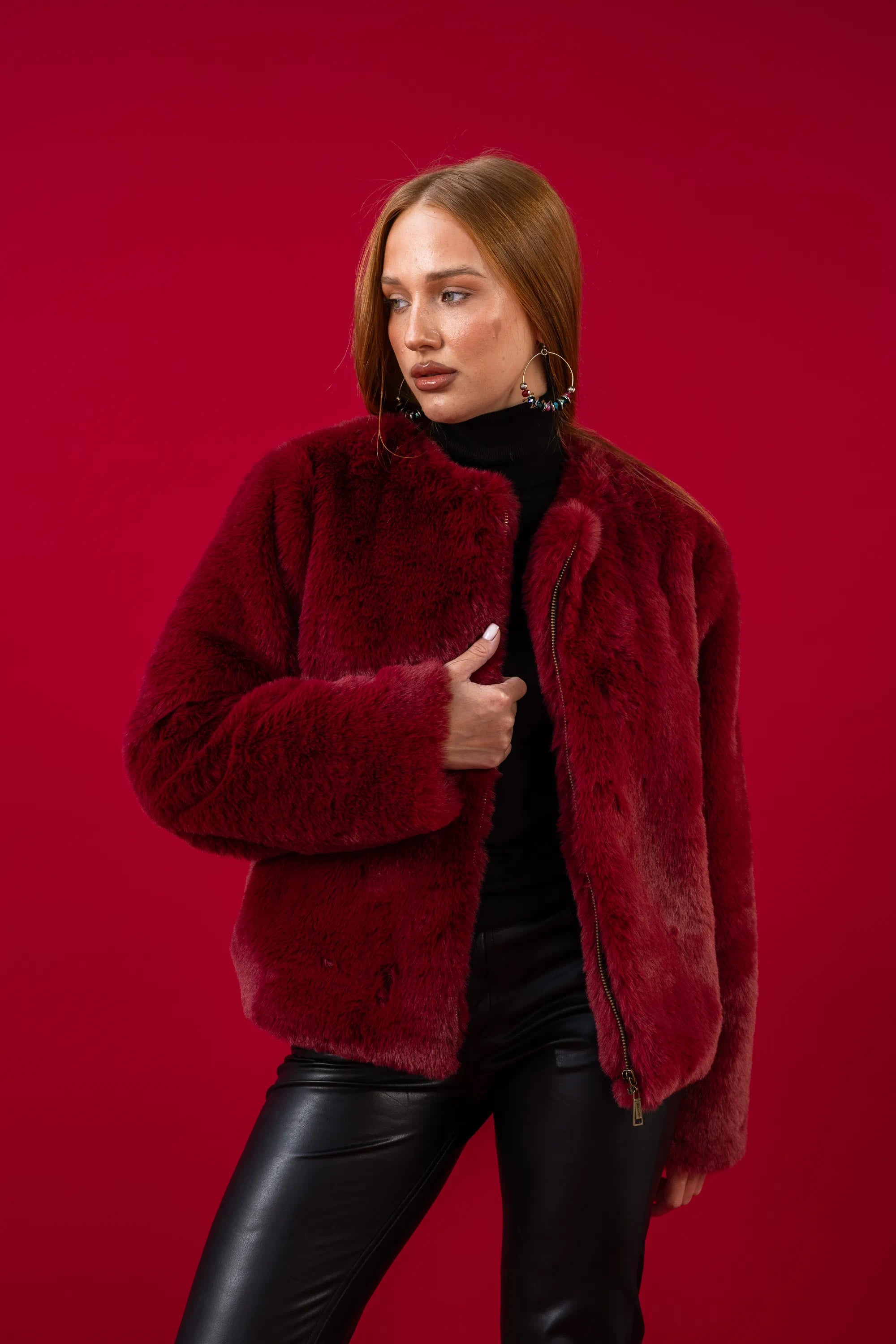 Woman wearing a red fur coat against a red background