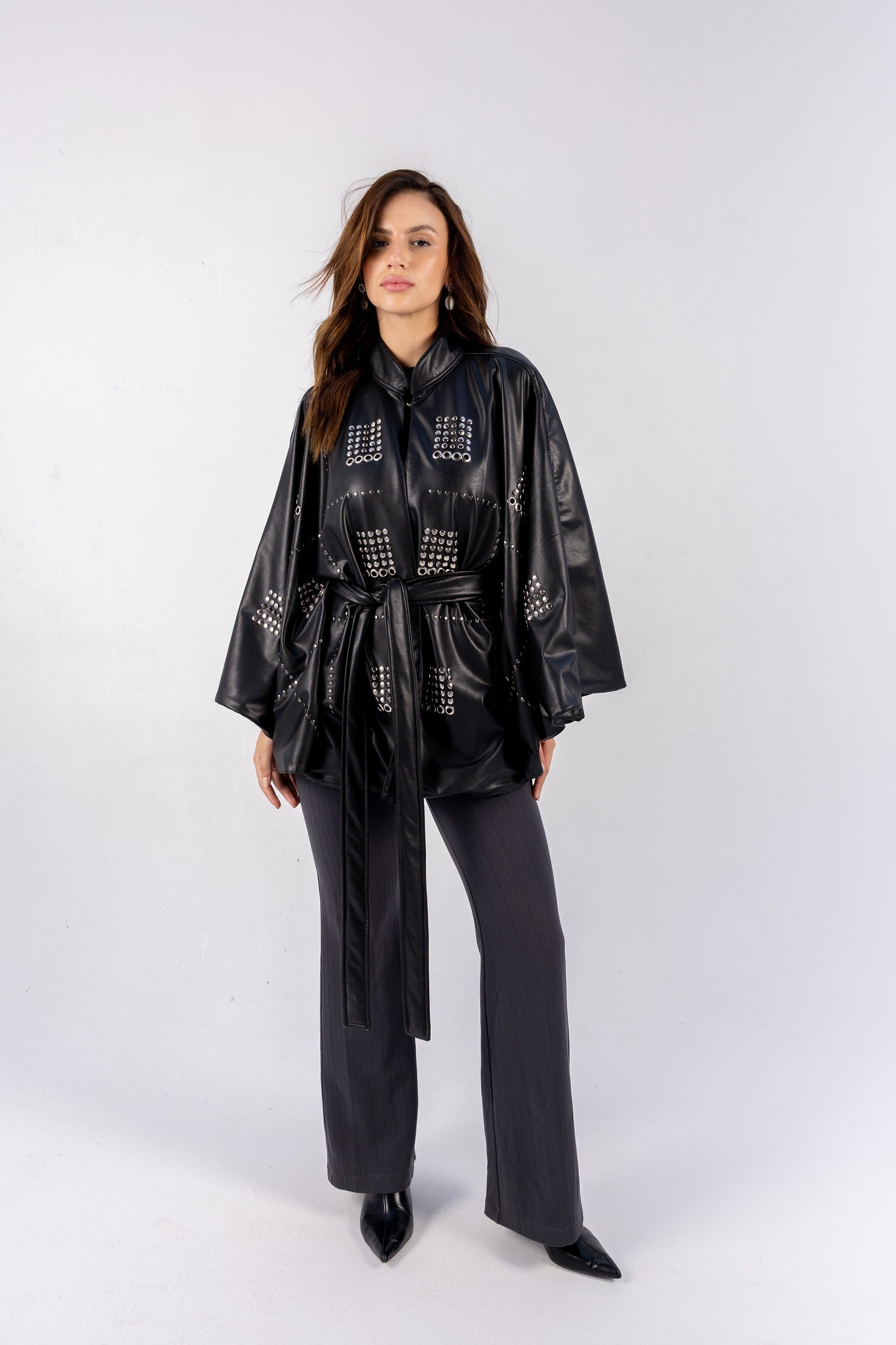 Woman wearing a black leather outfit with studded details on a white background