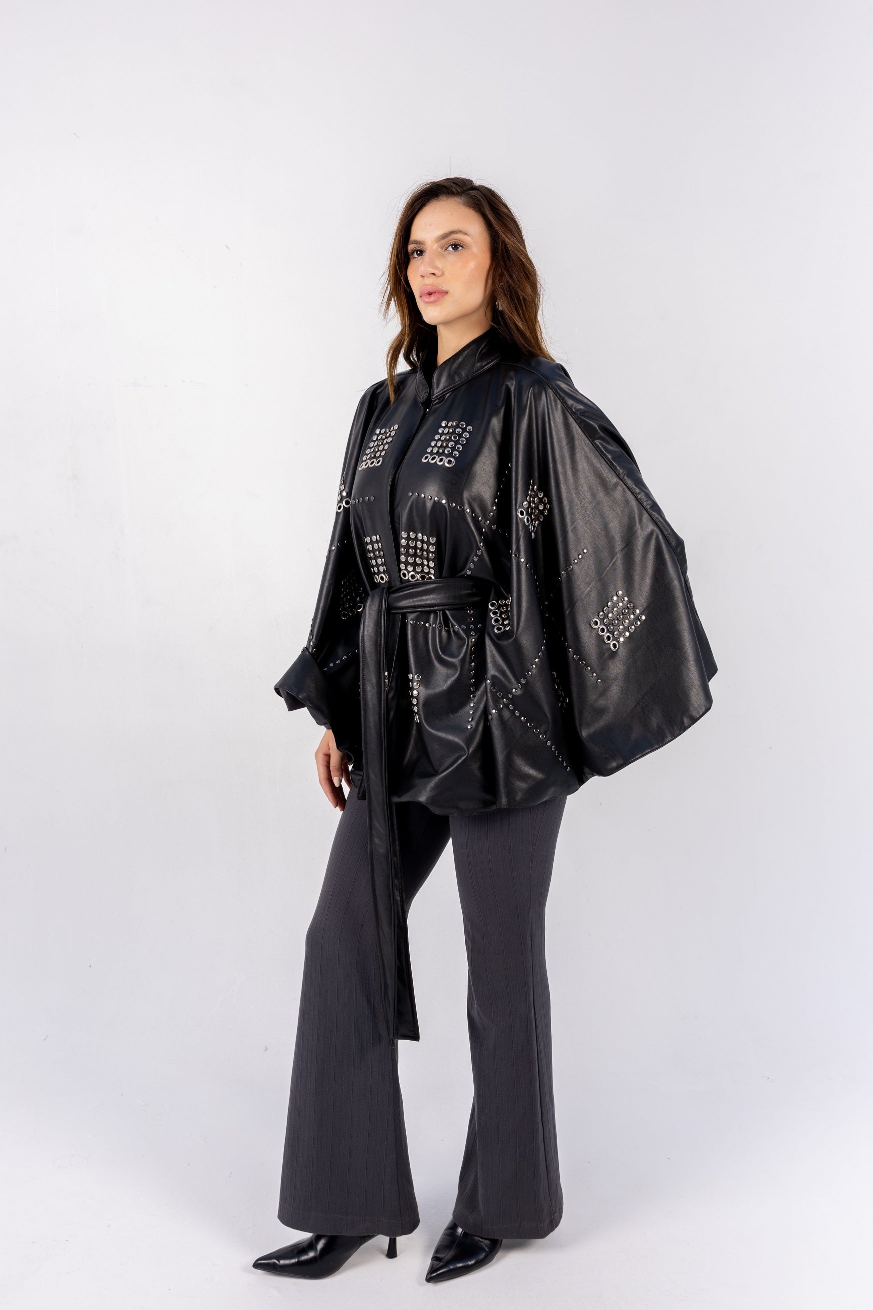 Woman wearing a black leather jacket with geometric patterns on a white background