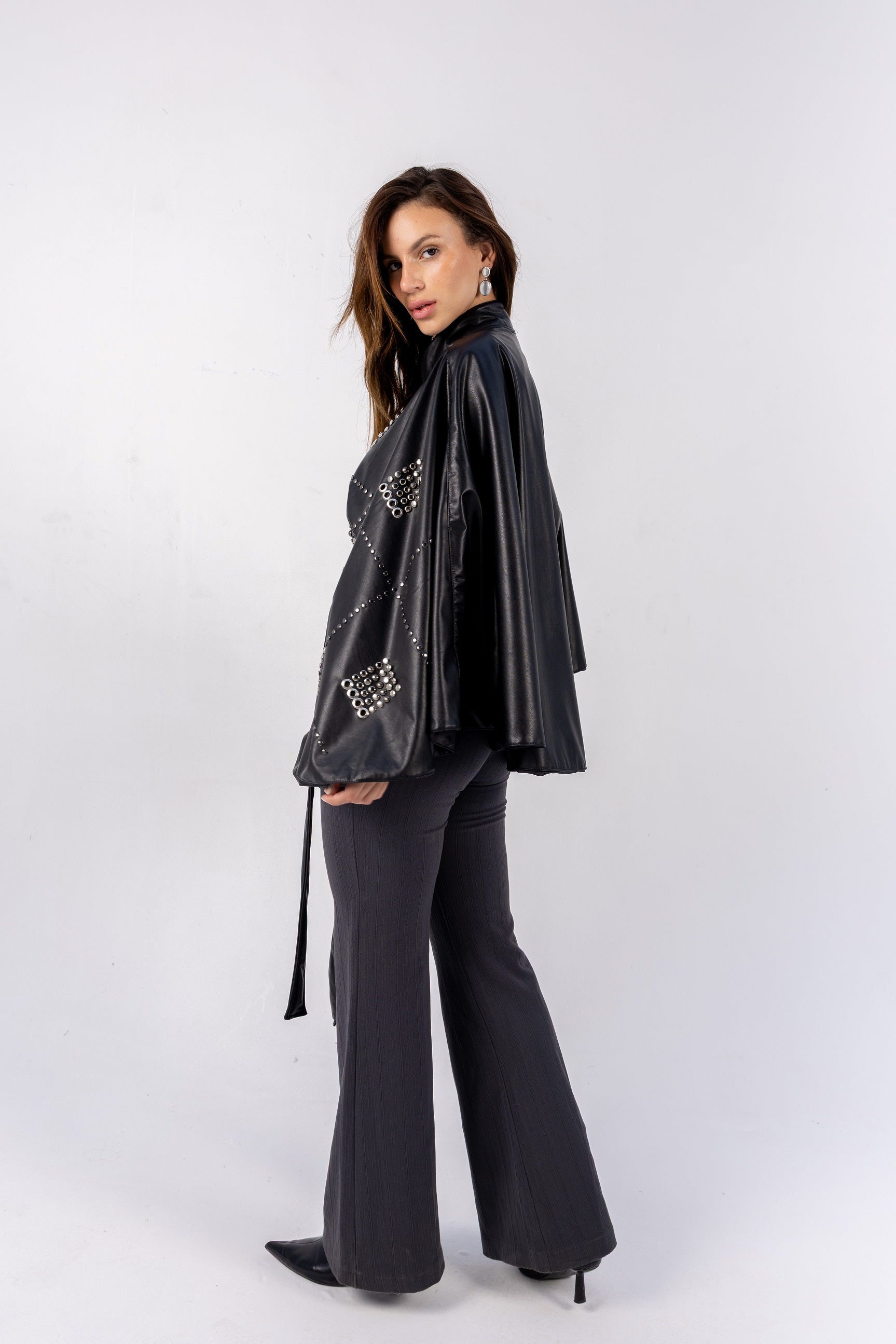 Woman wearing a black outfit with embellishments on a white background