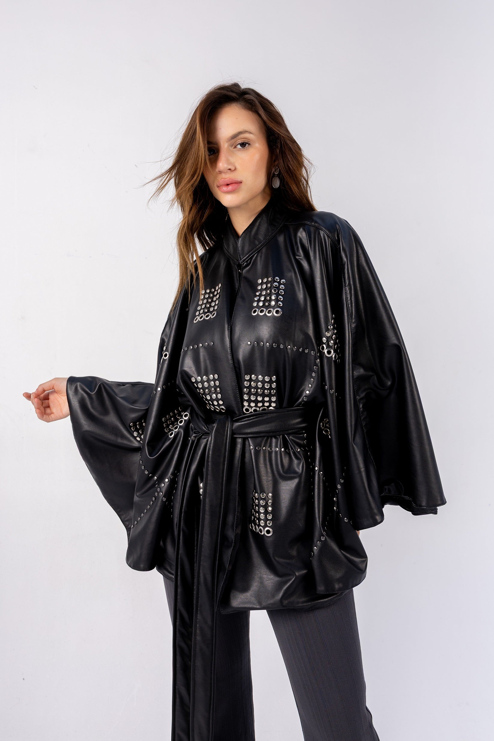 Woman wearing a black leather outfit with studded details on a white background