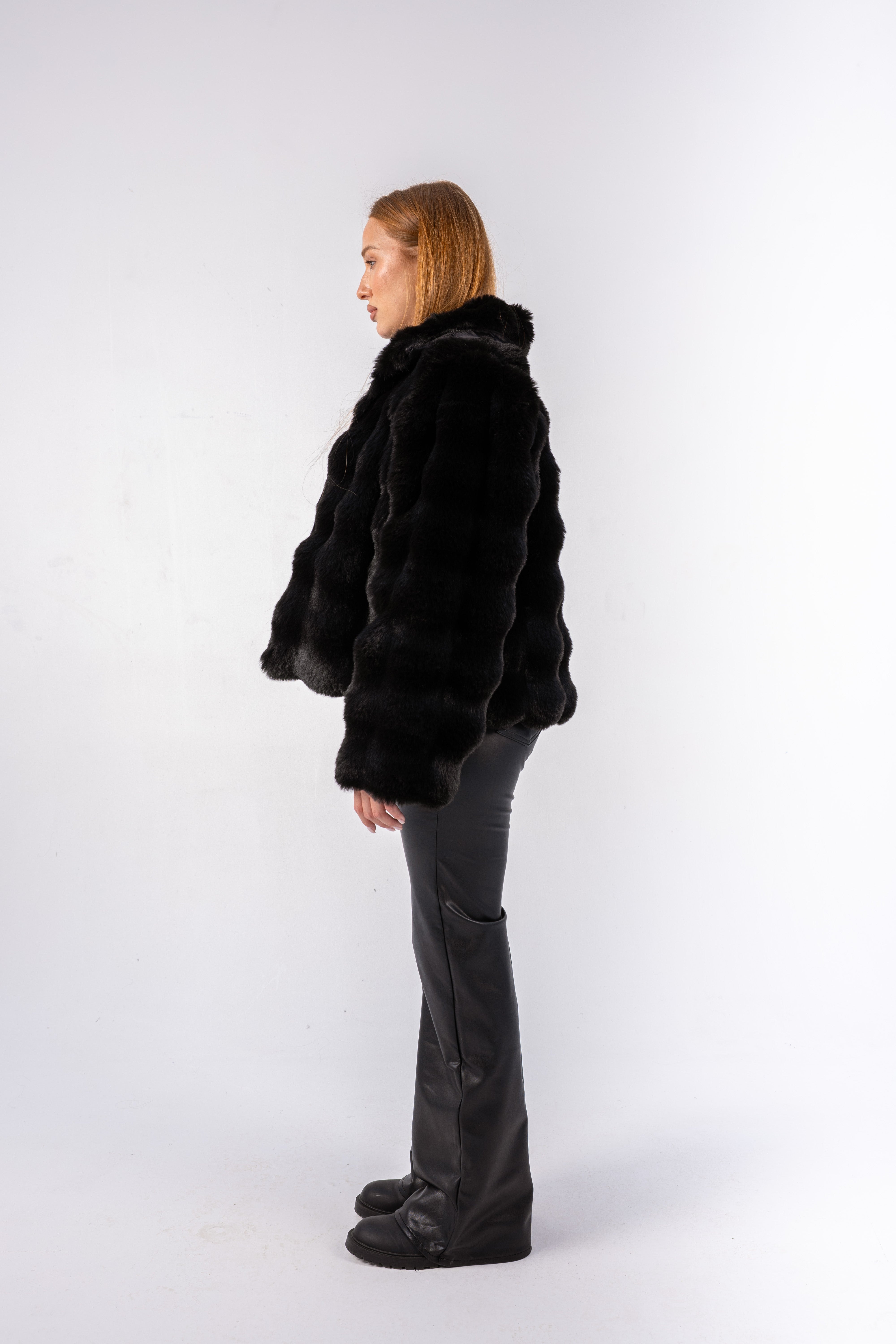 Person wearing a black fur coat and pants on a white background