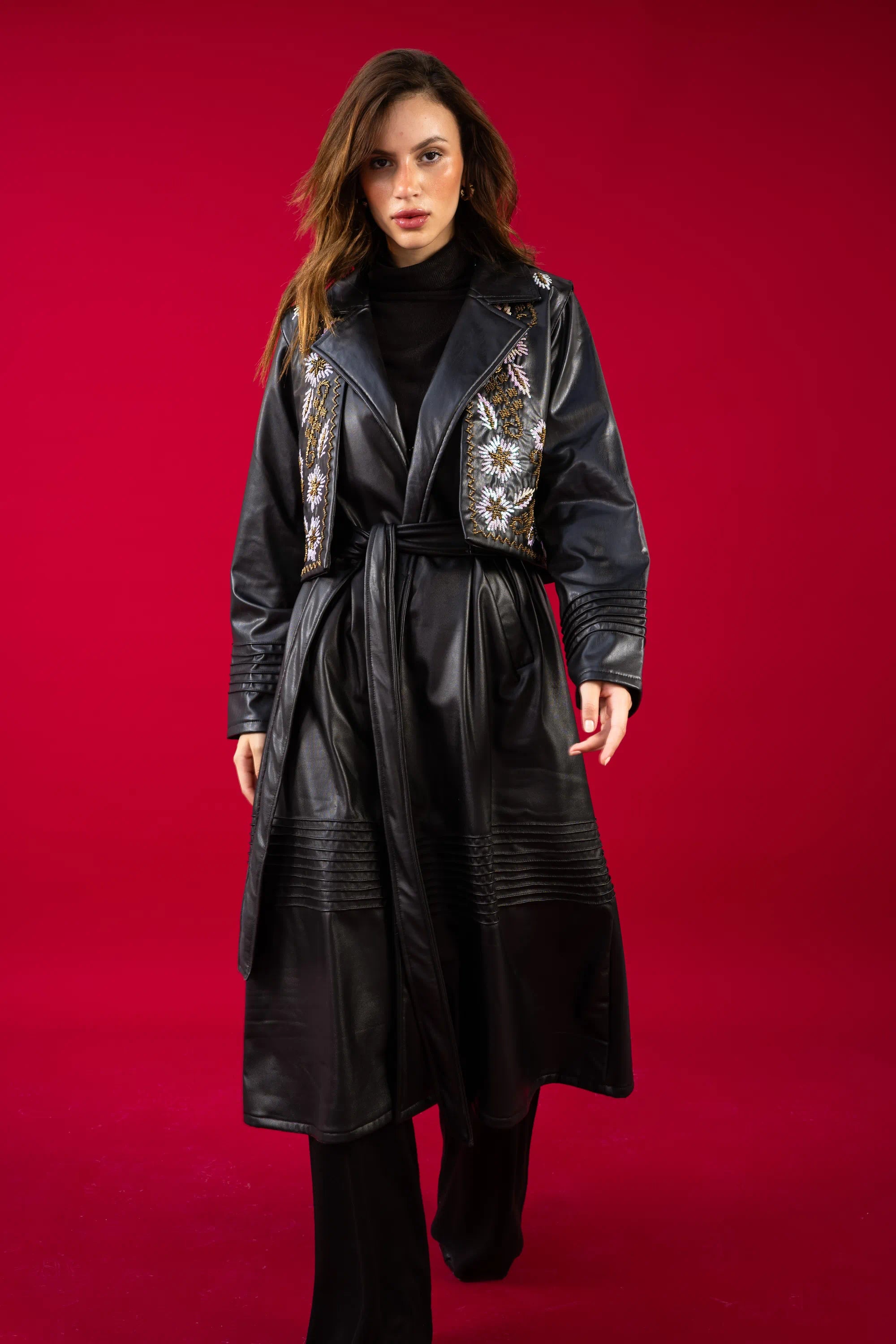 Woman wearing a black leather coat with floral patterns on a red background