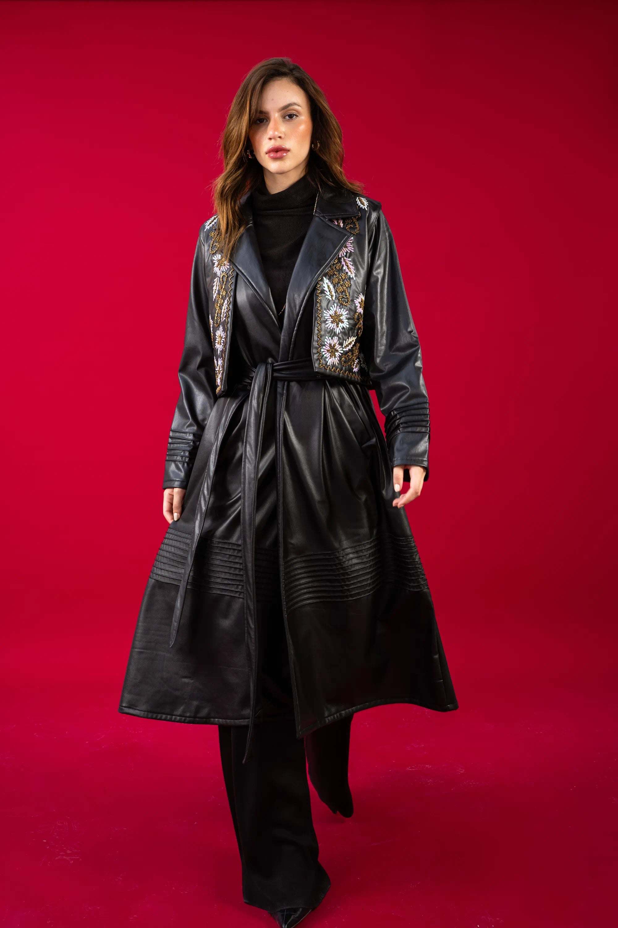 Woman wearing a black leather coat with floral embroidery on a red background