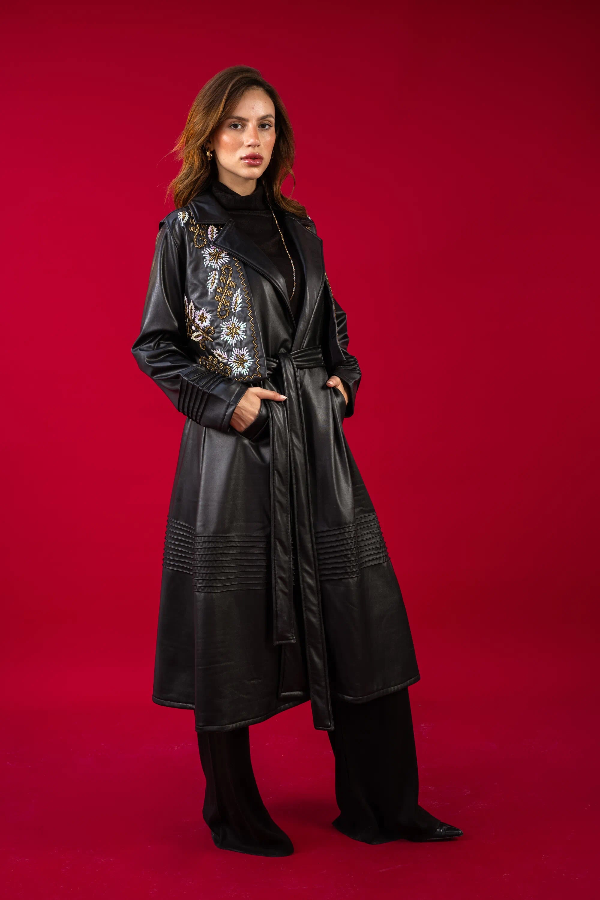 Woman wearing a black leather coat with floral embroidery on a red background