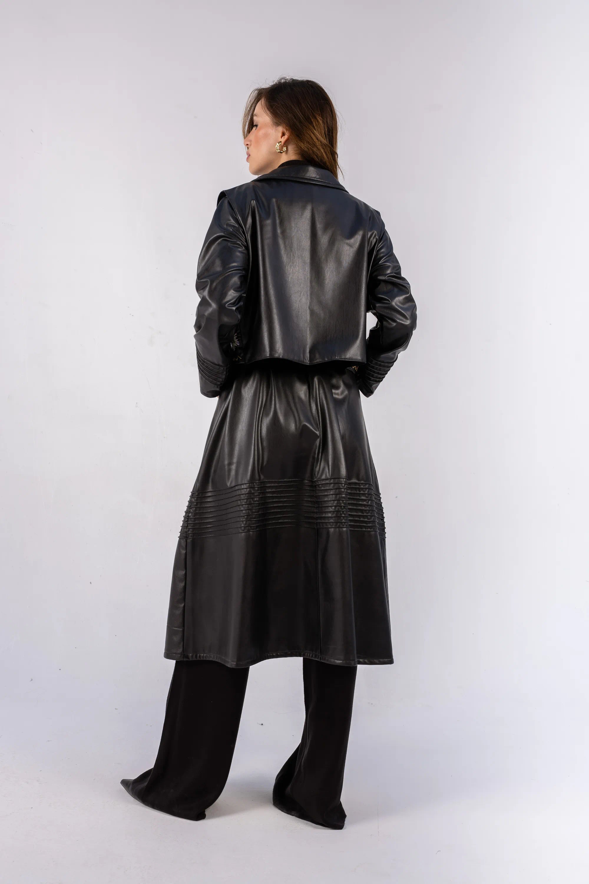Person wearing a black leather trench coat on a white background