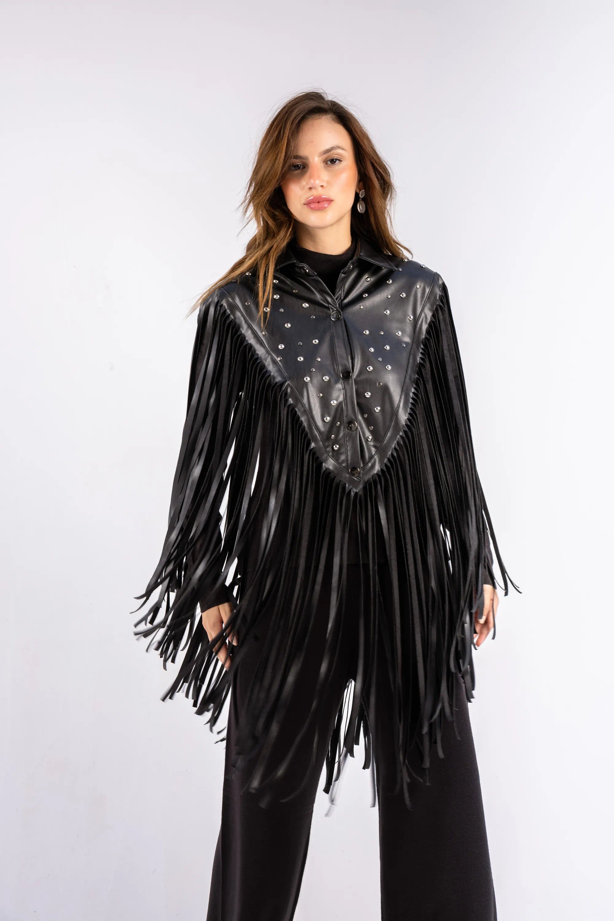 Woman wearing a black leather fringe outfit with a white background