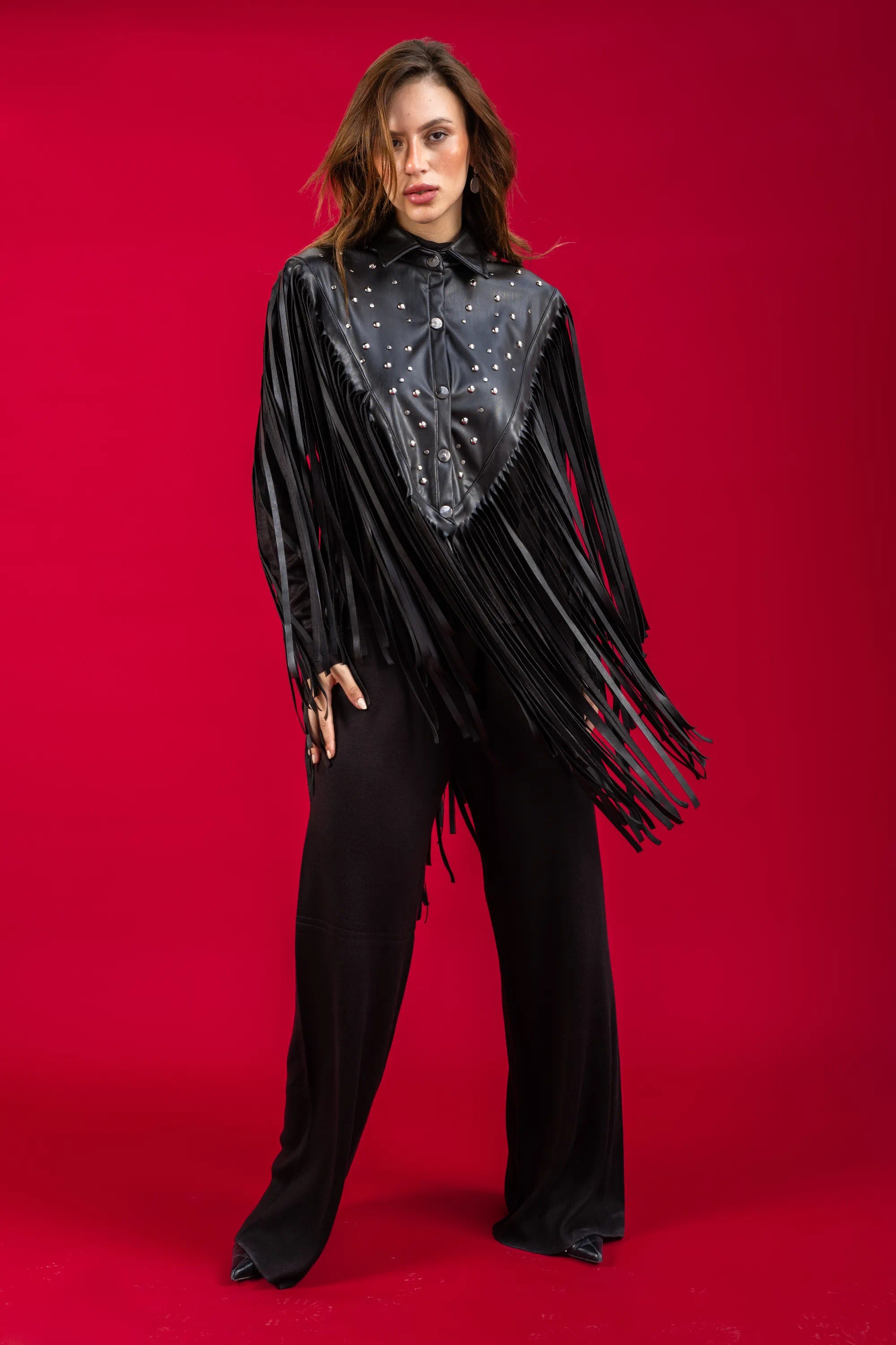 Person wearing a black fringe outfit with a red background