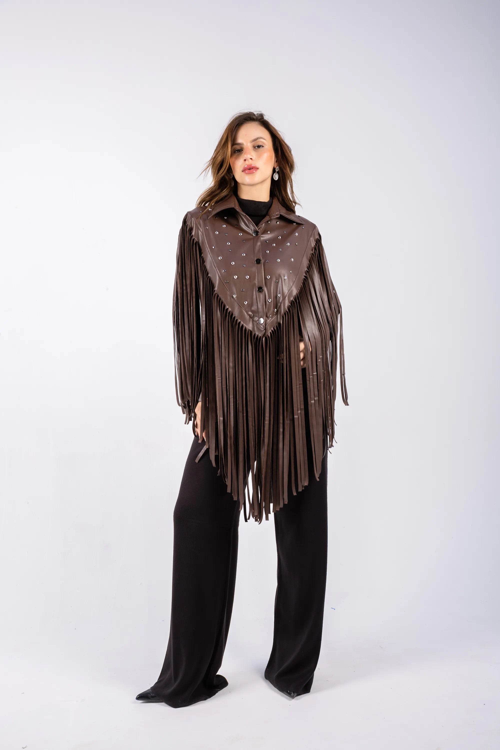 Woman wearing a brown fringe jacket over a black top and pants on a white background