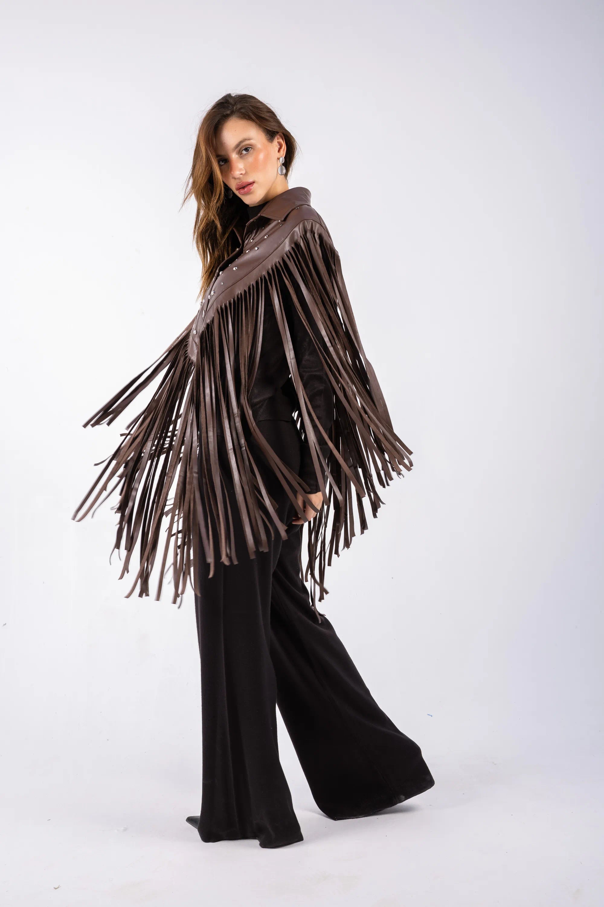 Woman wearing a brown fringe poncho against a white background