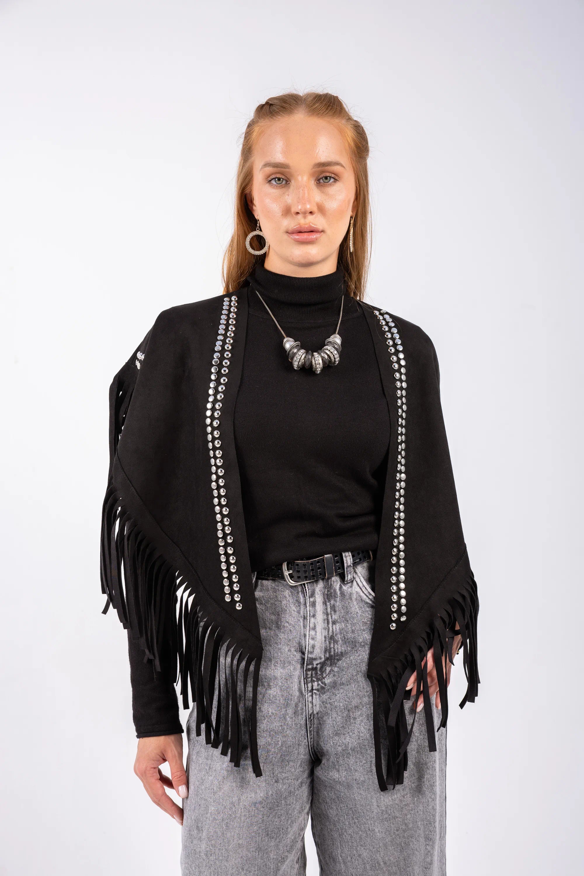 Person wearing a black fringe jacket with silver studs on a white background