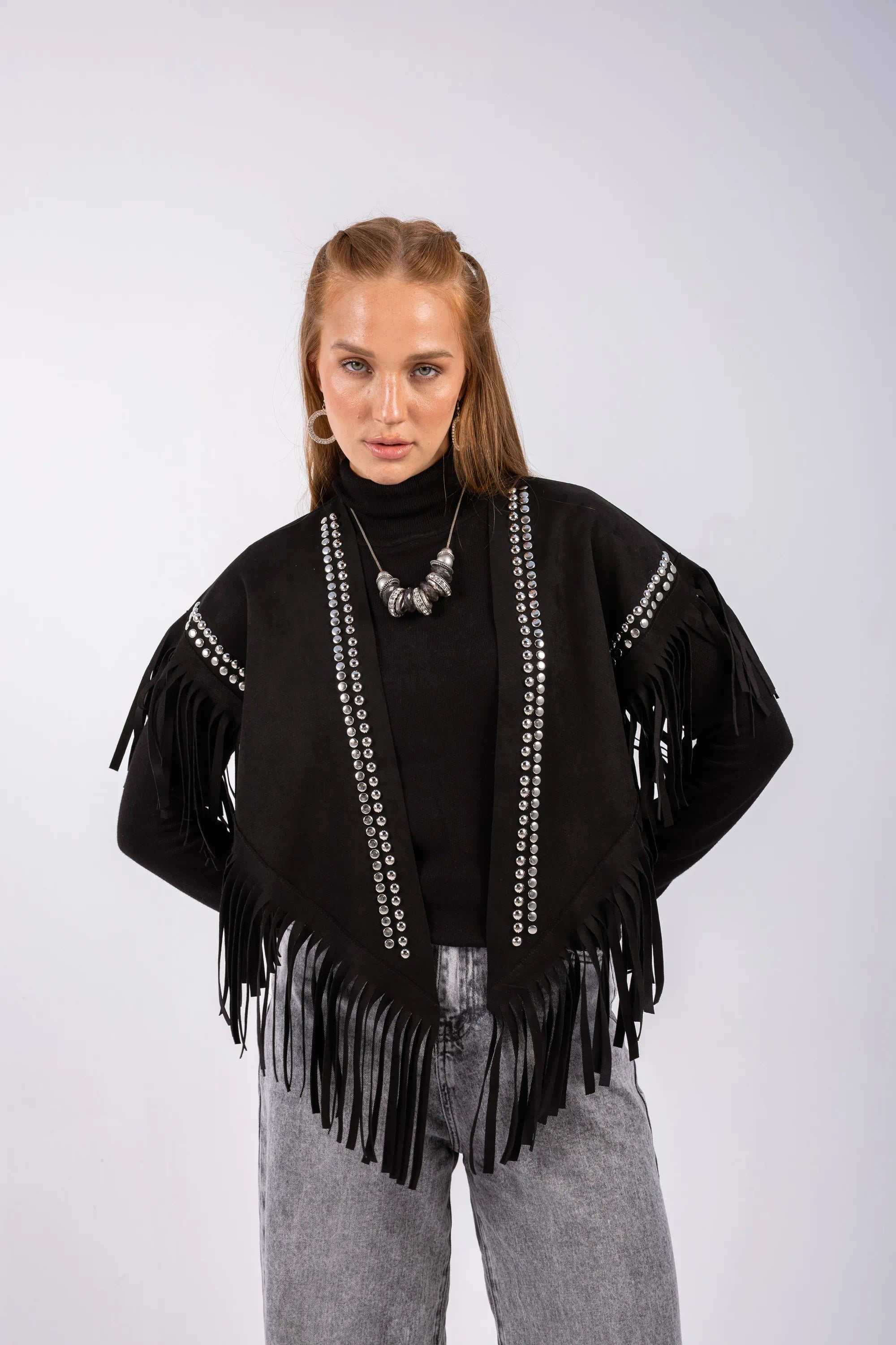 Woman wearing a black fringe jacket with white embellishments on a white background