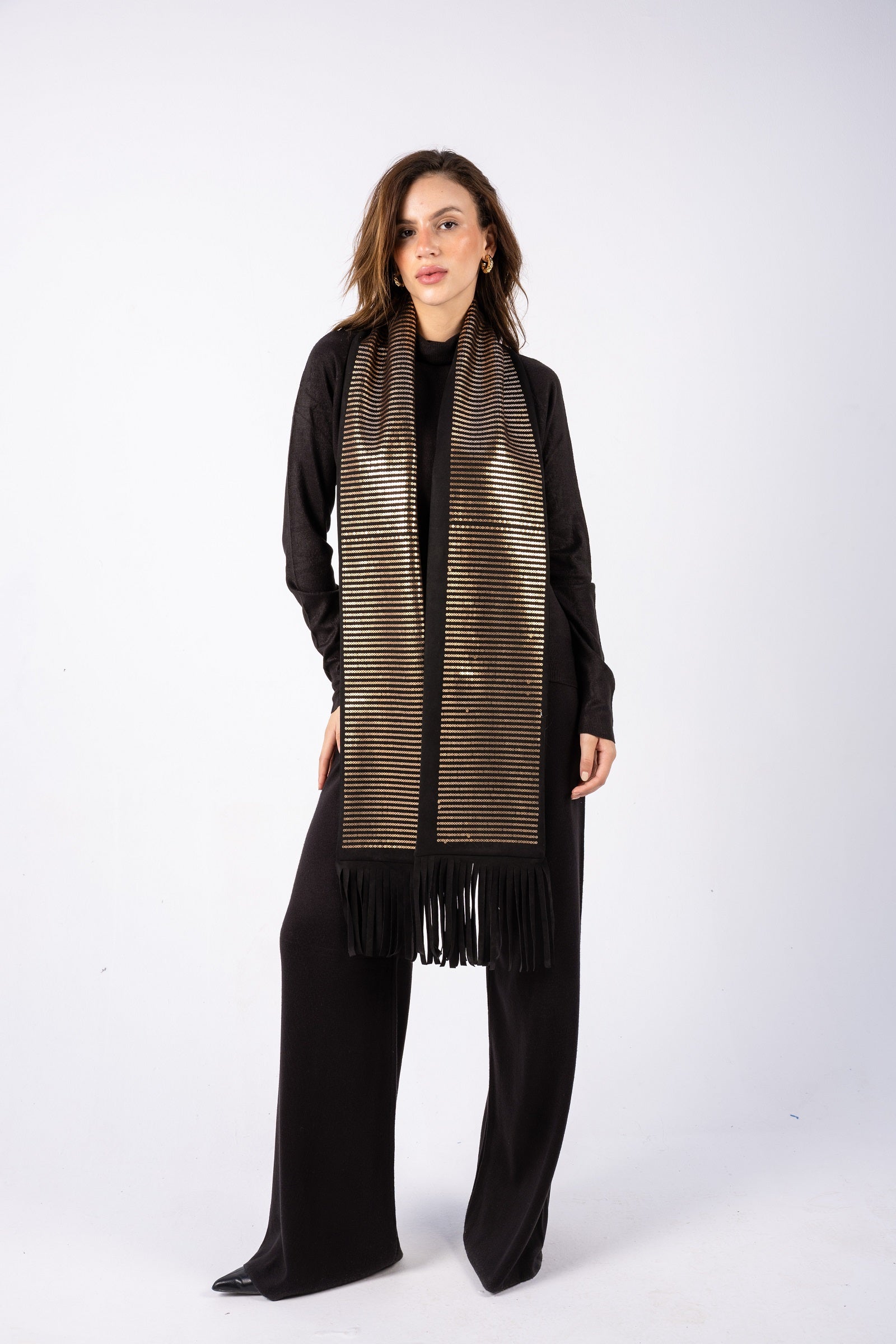 Woman wearing a long, patterned scarf with fringe on a white background