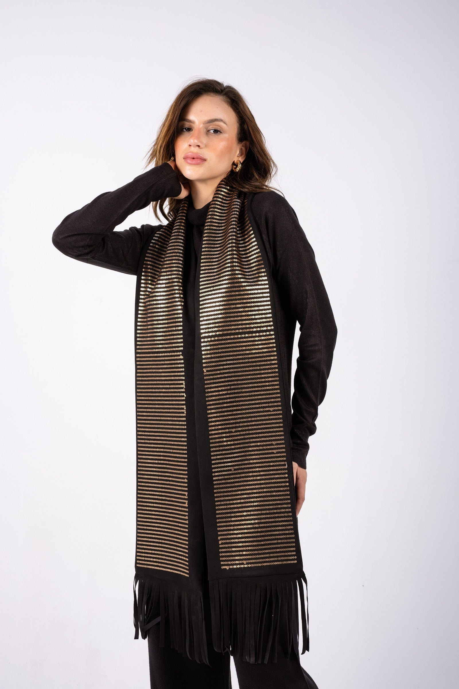 Woman wearing a long, patterned scarf with fringe on a white background