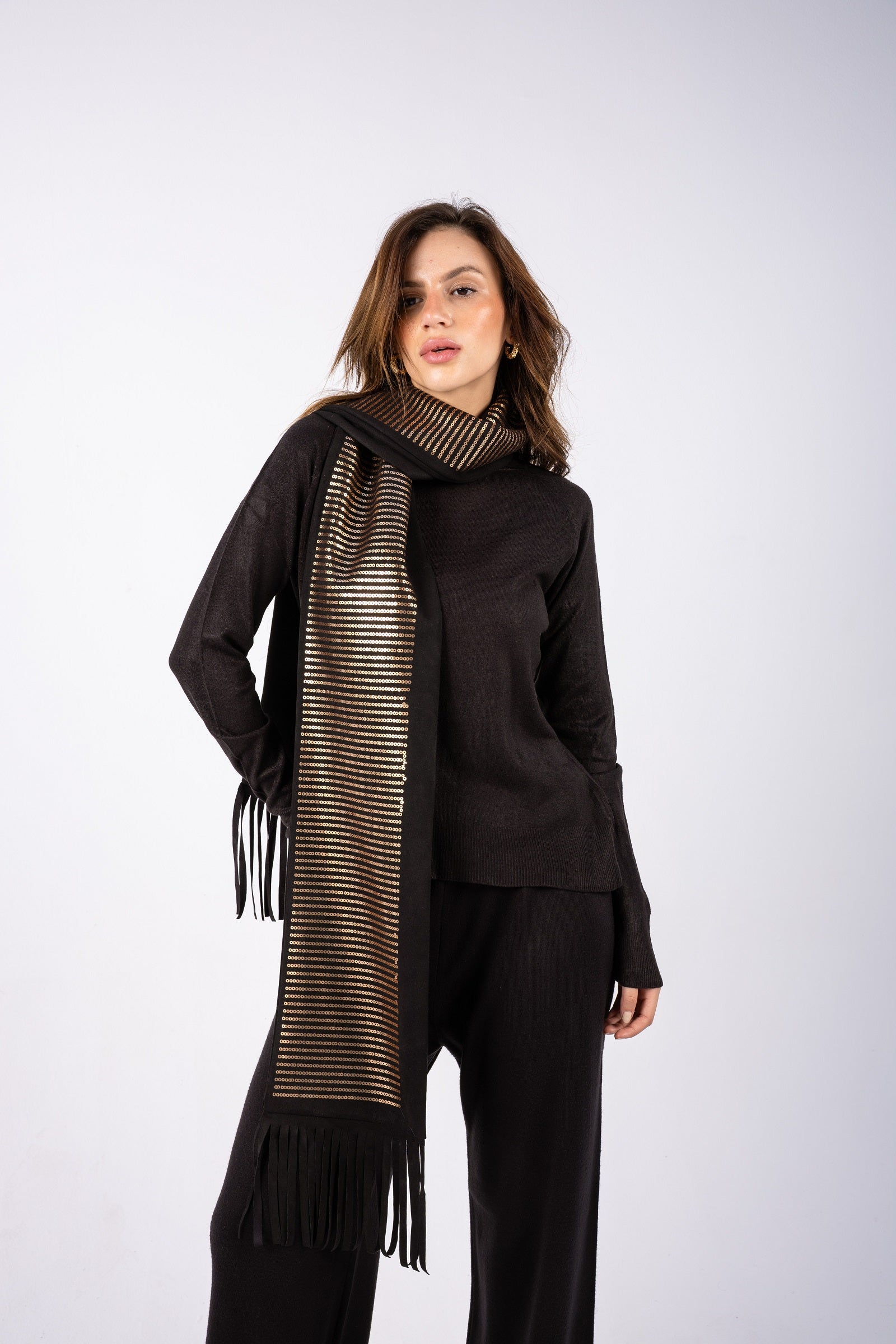 Woman wearing a black outfit with a long, patterned scarf on a white background