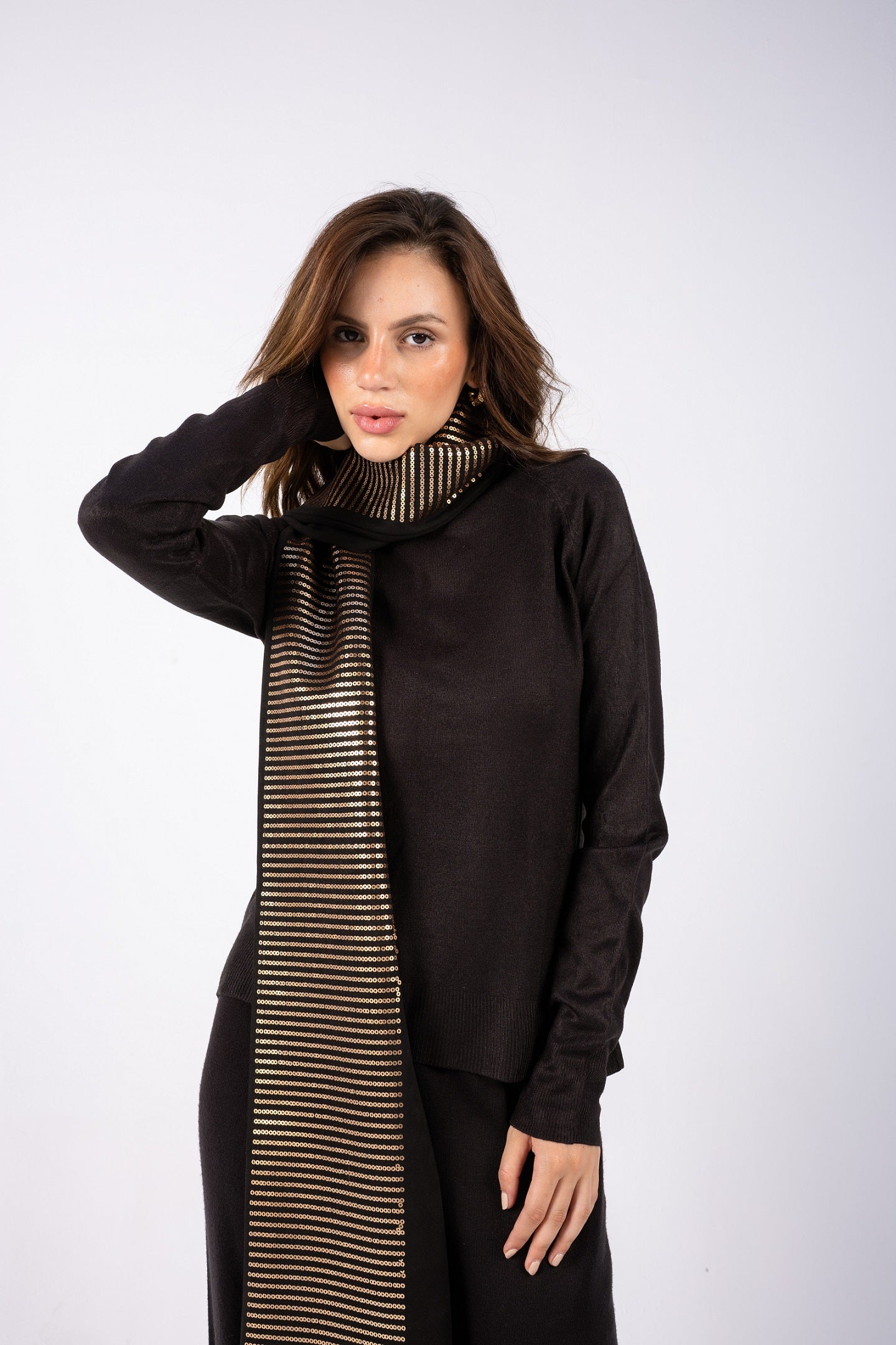 Woman wearing a black outfit with a striped scarf on a white background