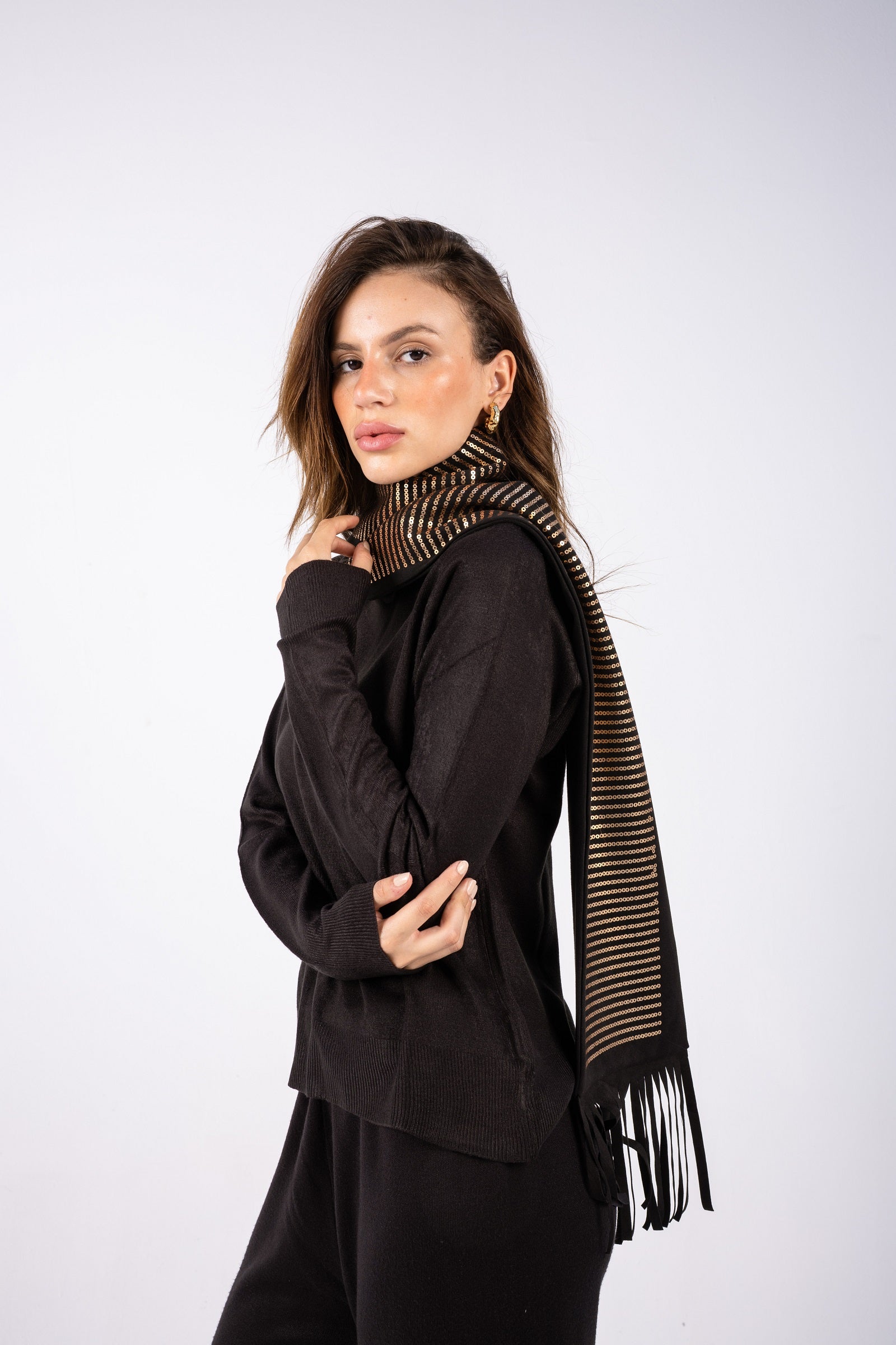 Woman wearing a black outfit with a striped scarf on a white background