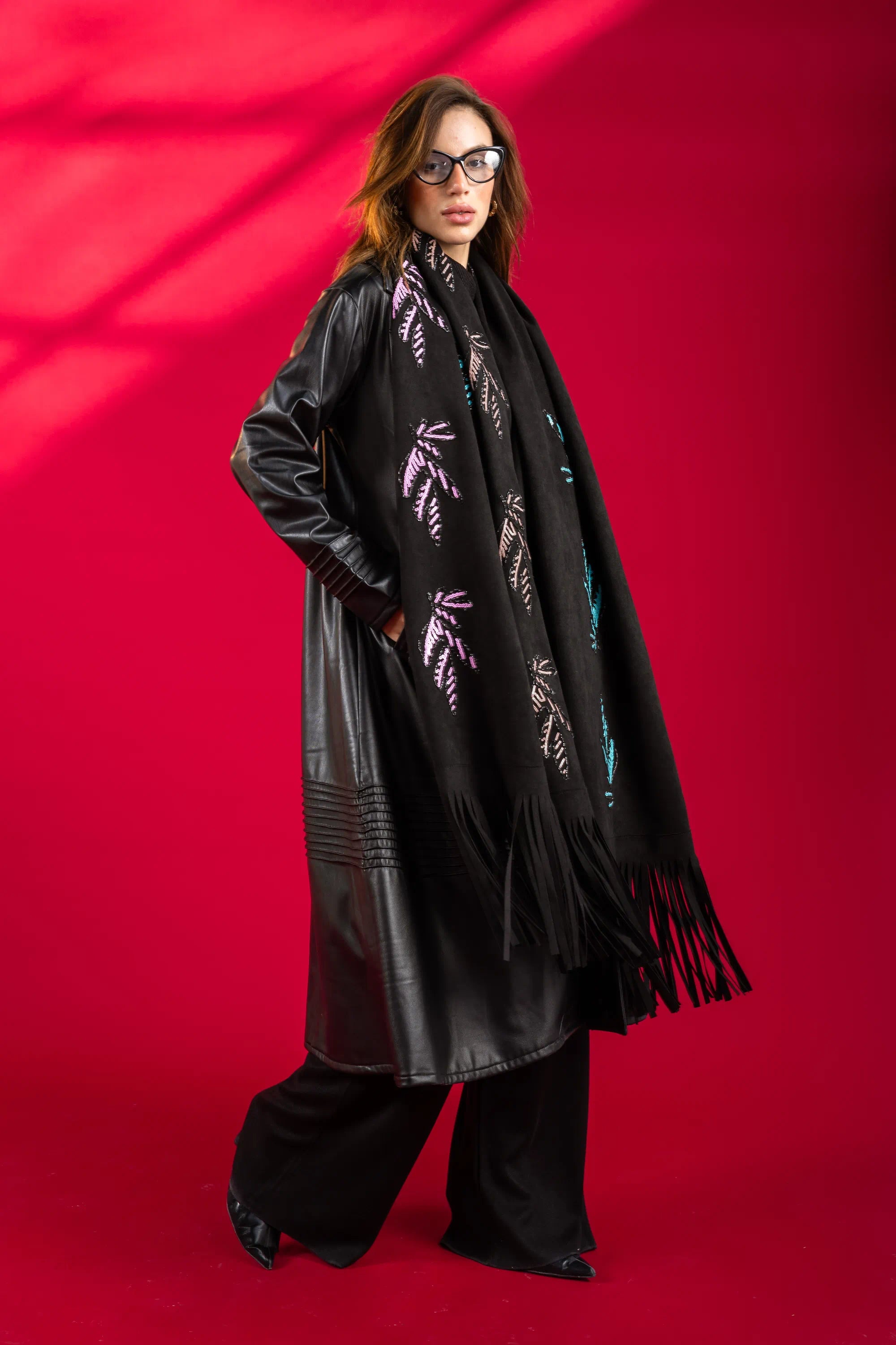 Person wearing a black leather jacket and scarf with floral patterns on a red background