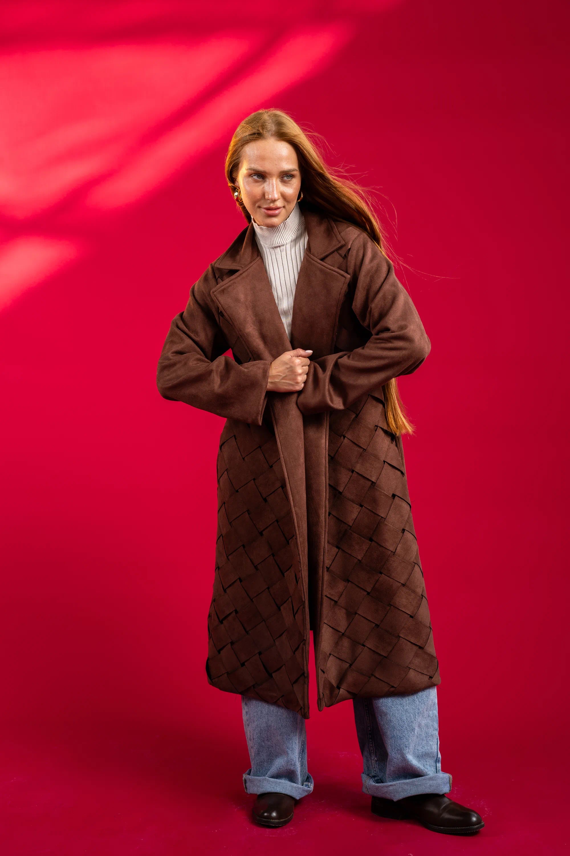 Person wearing a brown quilted coat on a red background