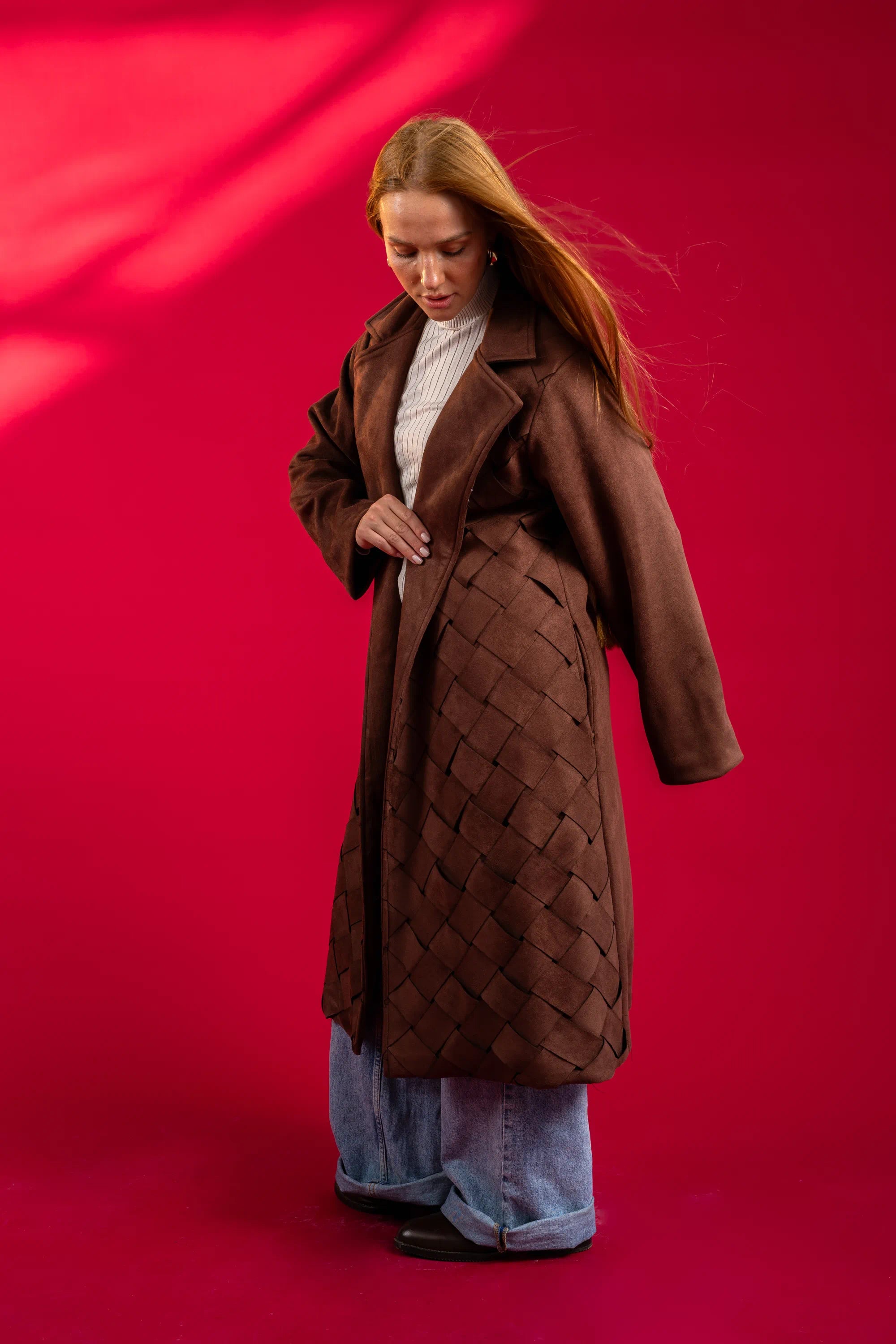 Person wearing a brown quilted coat against a red background