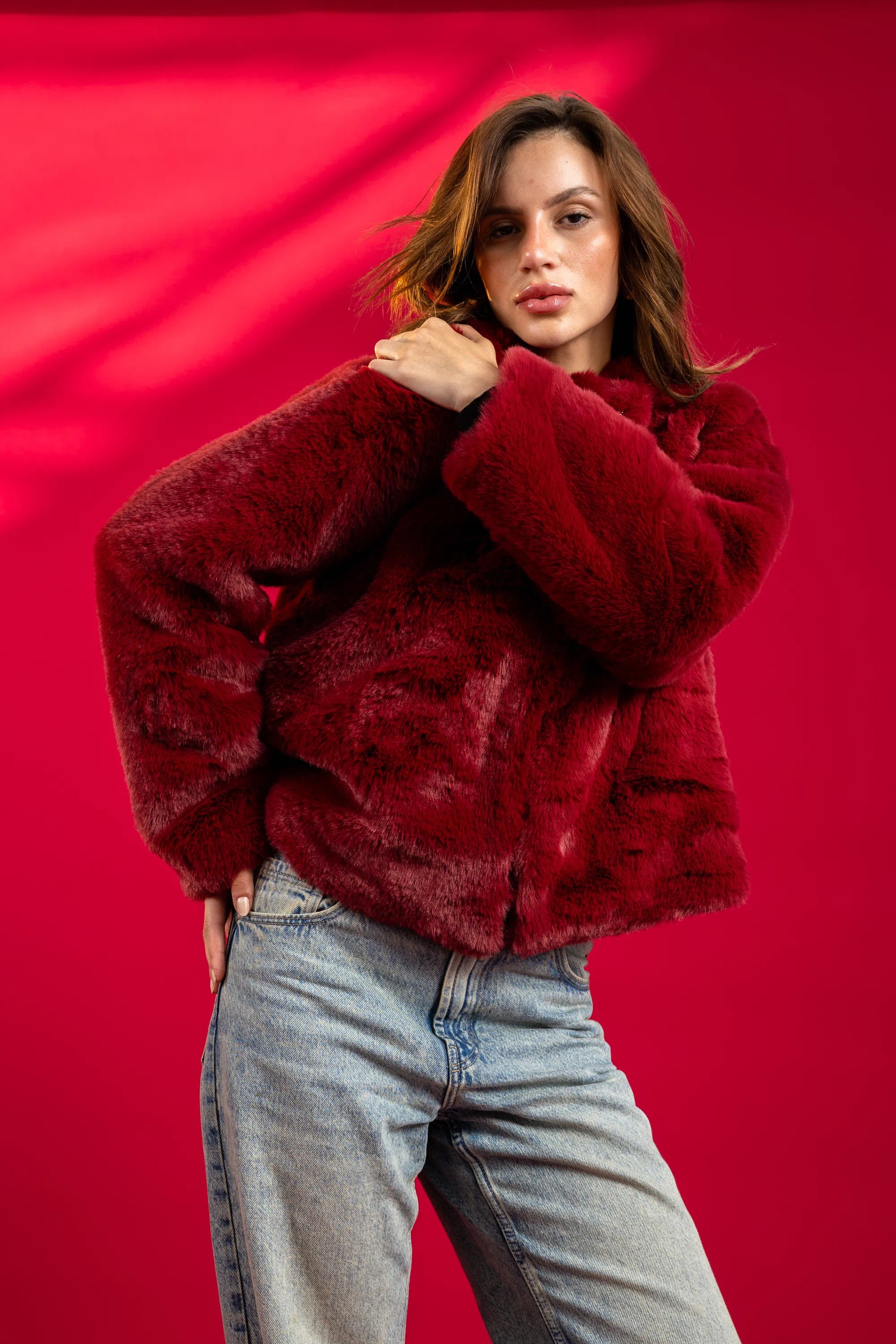 Person wearing a red fur coat against a red background