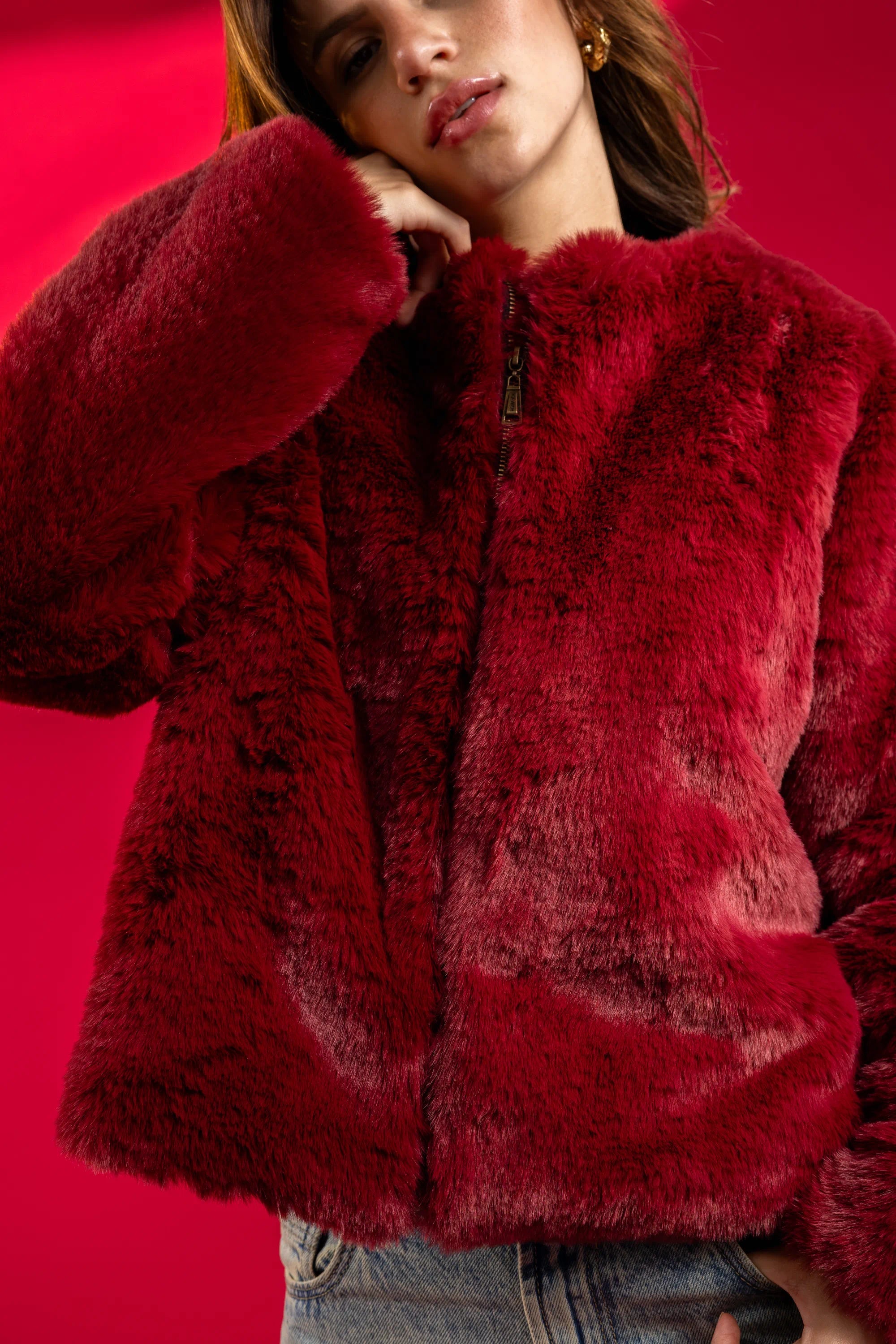 Person wearing a red fluffy jacket against a red background
