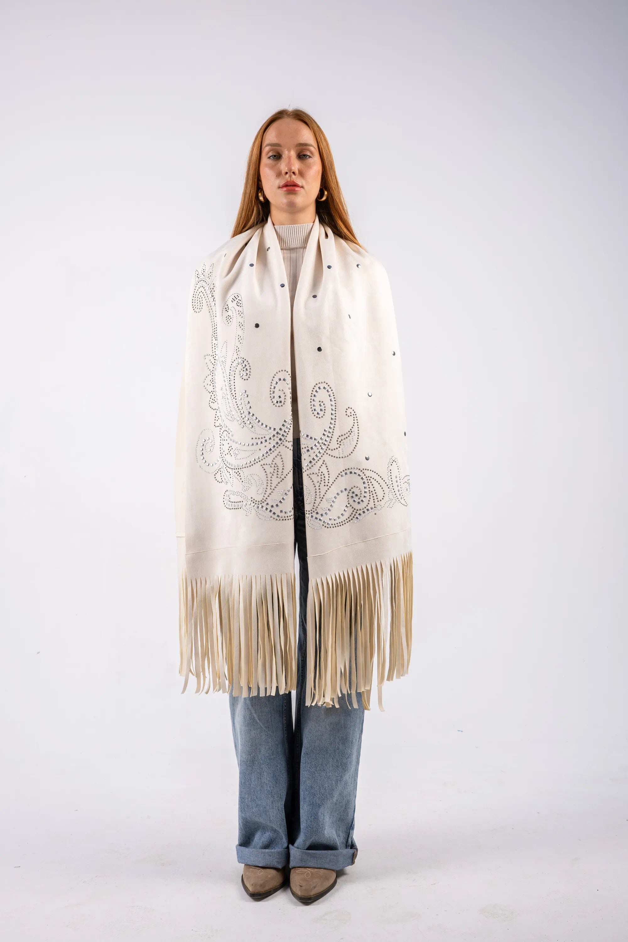 Person wearing a large cream-colored scarf with fringe on a white background