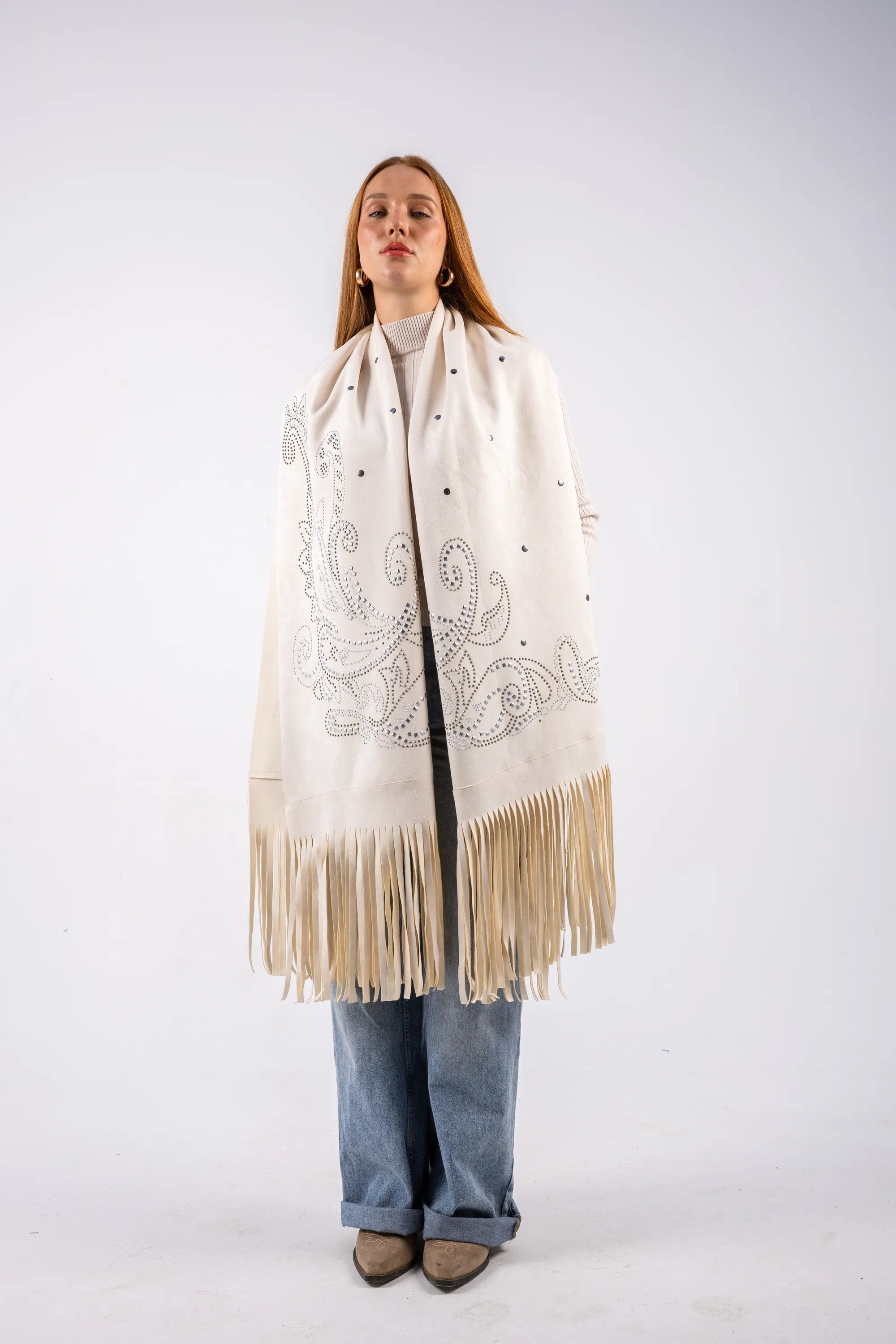 Person wearing a cream-colored scarf with fringe and embroidery on a white background