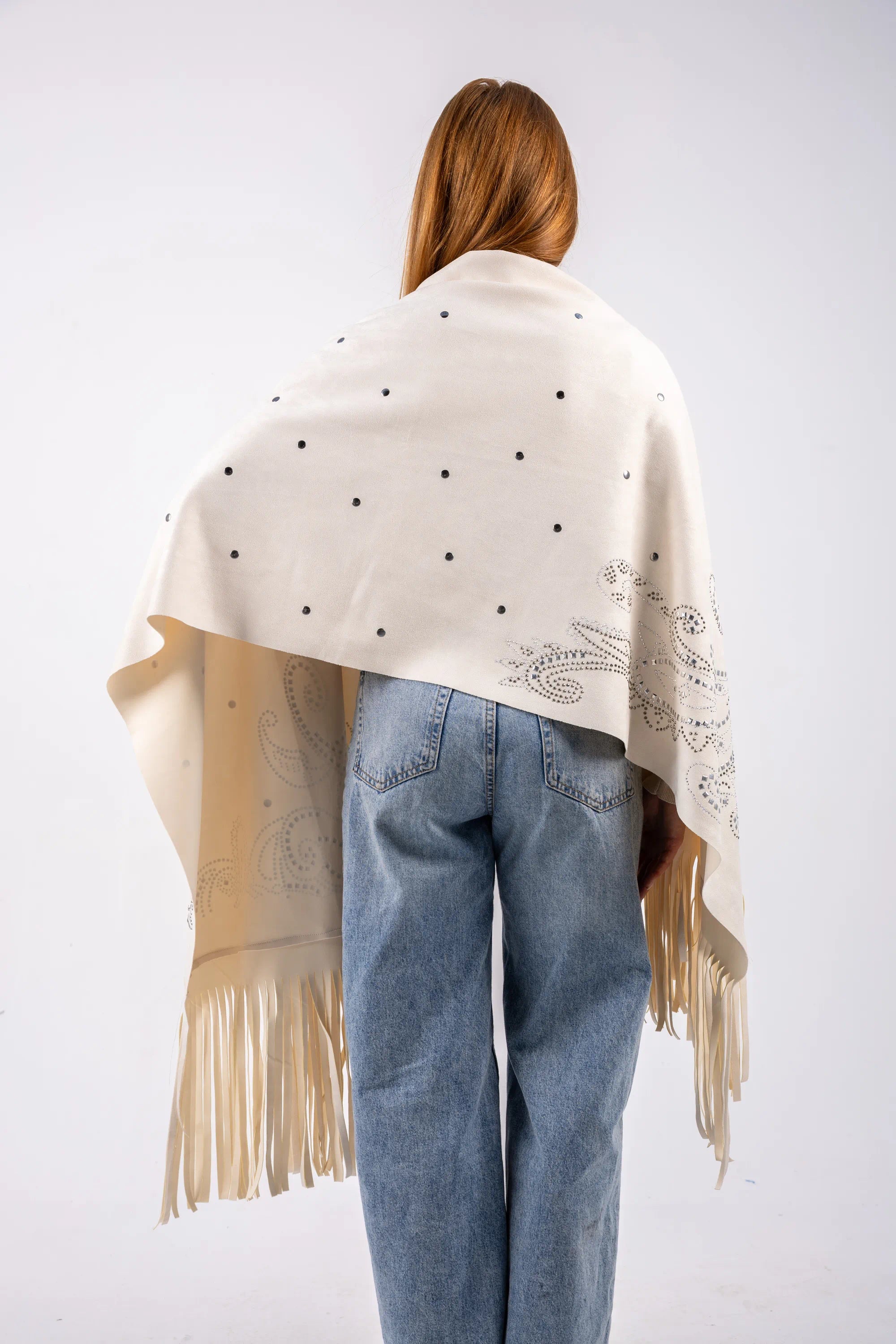 Person wearing a white shawl with black polka dots and fringe, standing against a white background