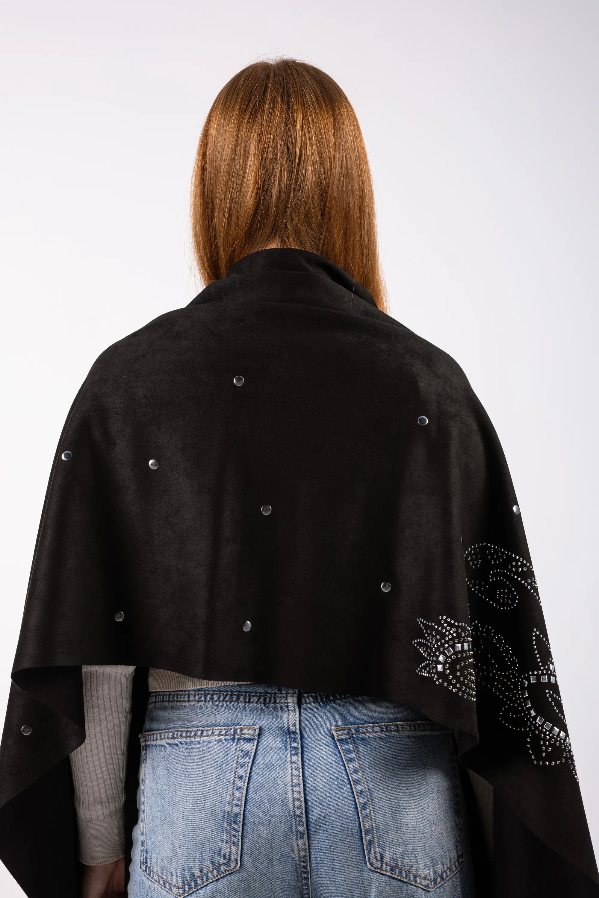 Person wearing a black poncho with decorative elements on a white background